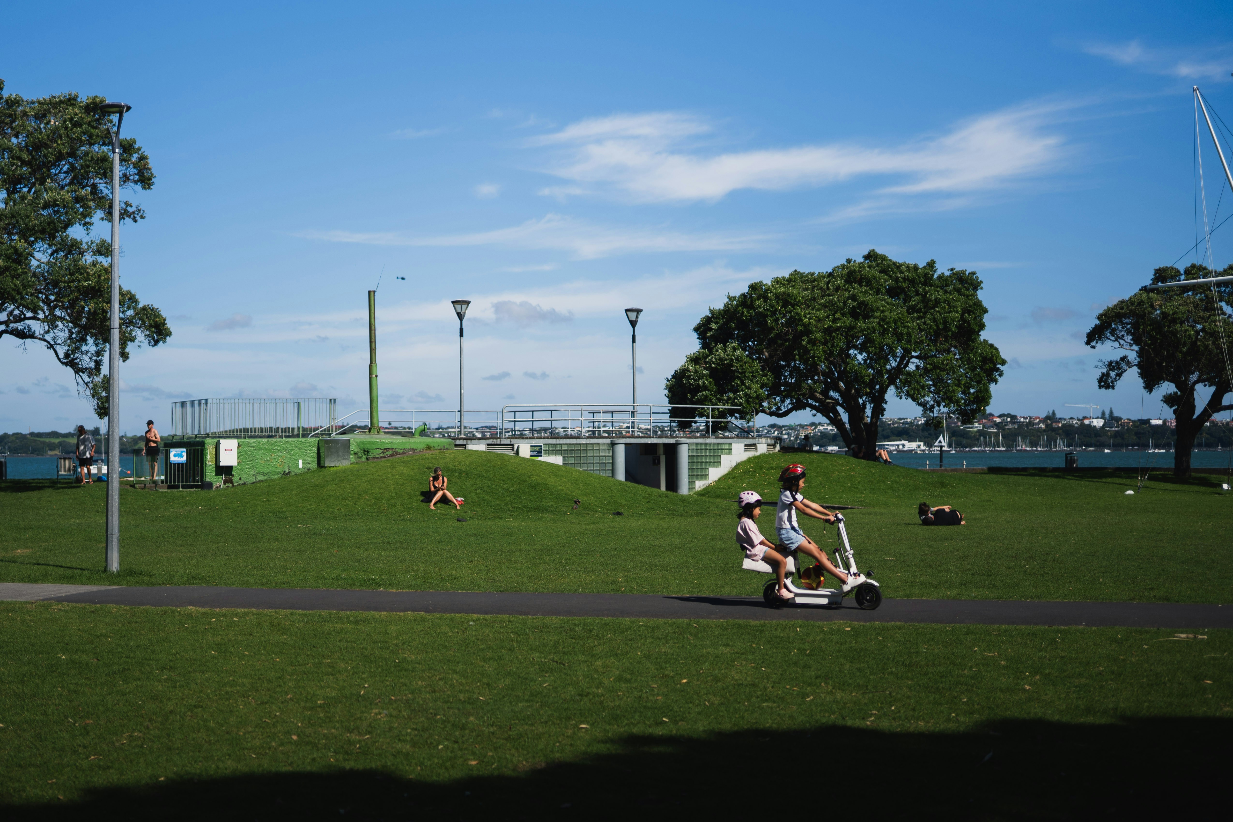 People enjoying electric scooters in a sunny park.