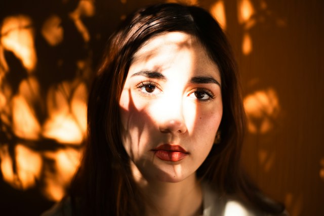 Sunlight and leaf shadows falling across a woman's face