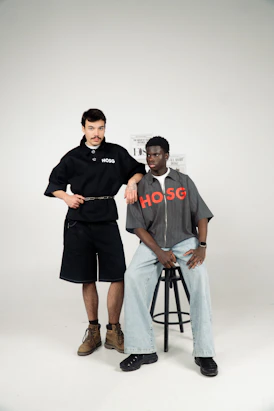 Two men posing in stylish streetwear on a white background.