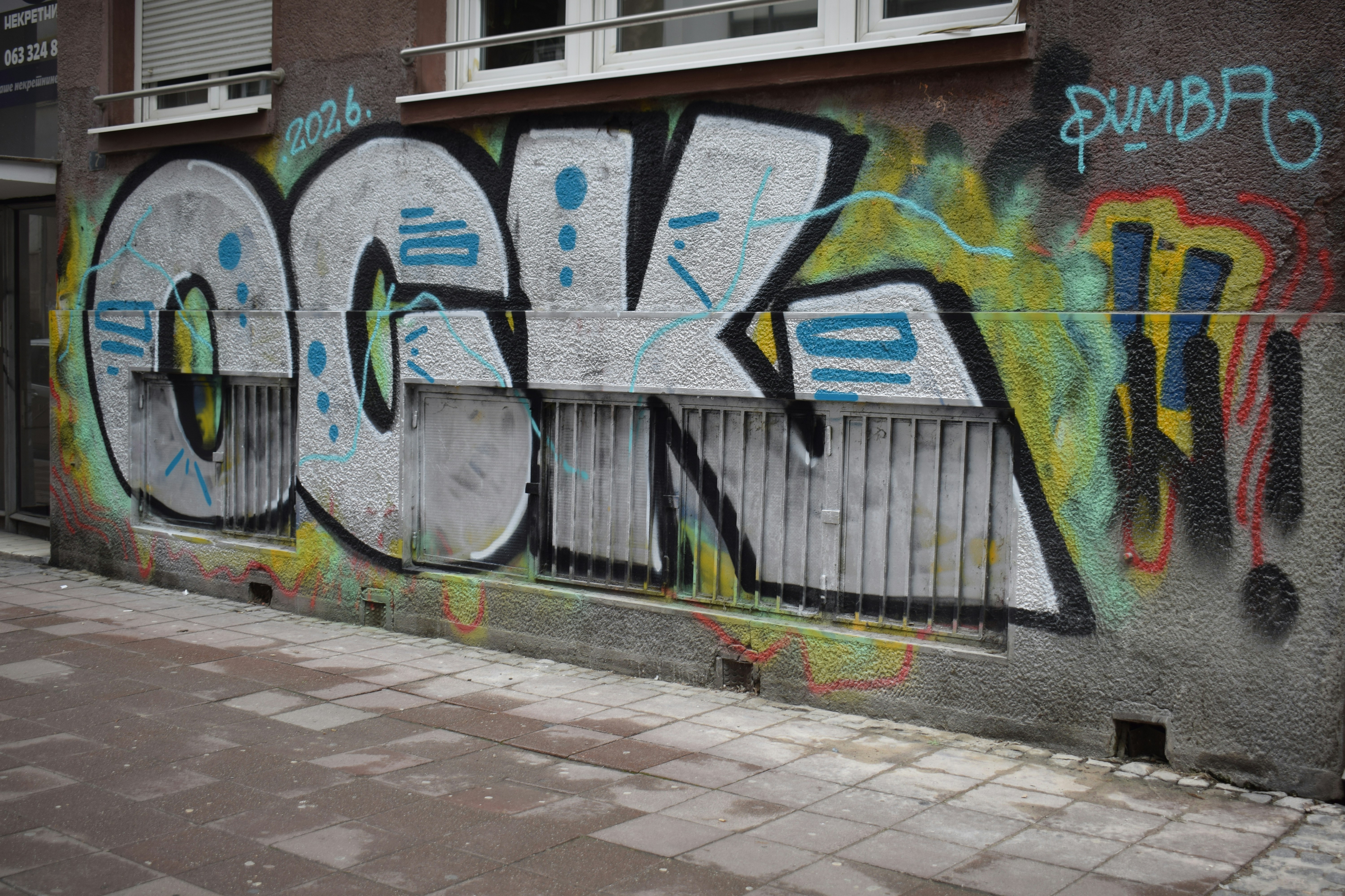 Graffiti art on a textured wall with barred window