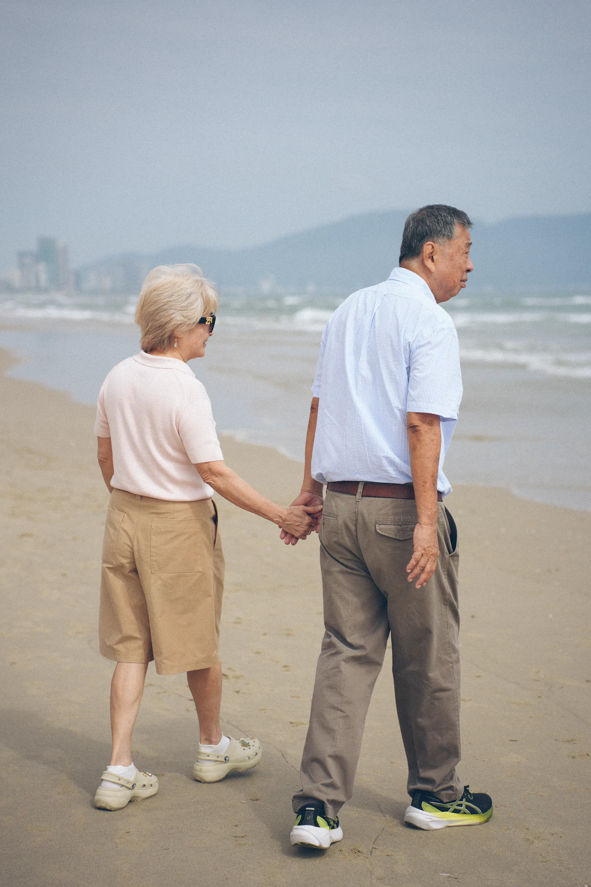 Pareja mayor caminando junta por la playa, vista desde atrás