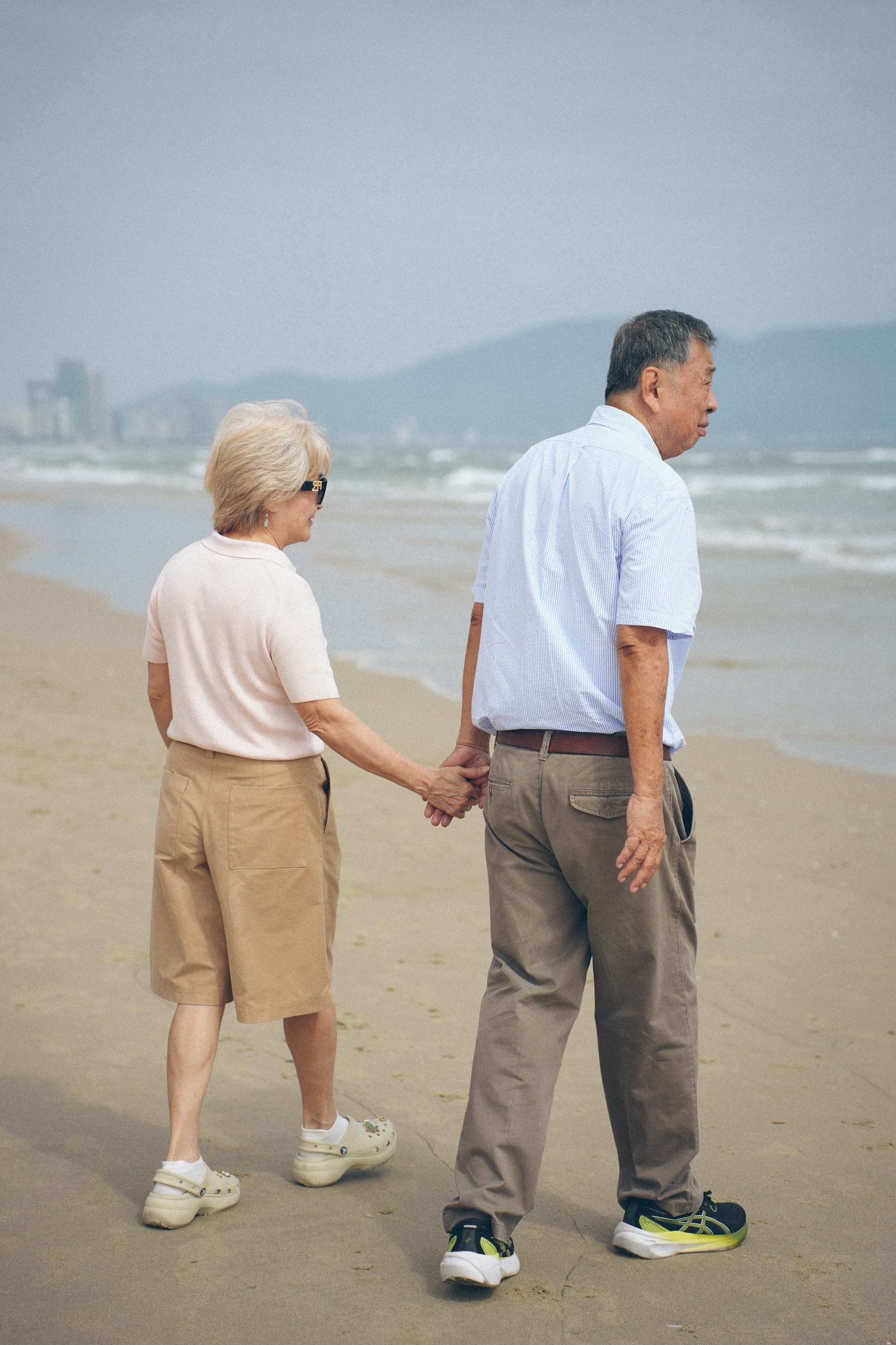 Elderly couple holding hands walking on a beach