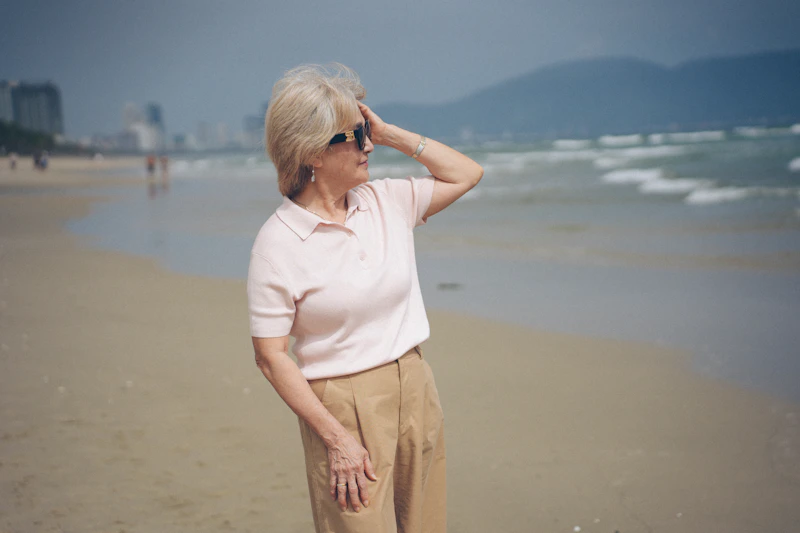 Elderly woman on a beach looking out at the ocean