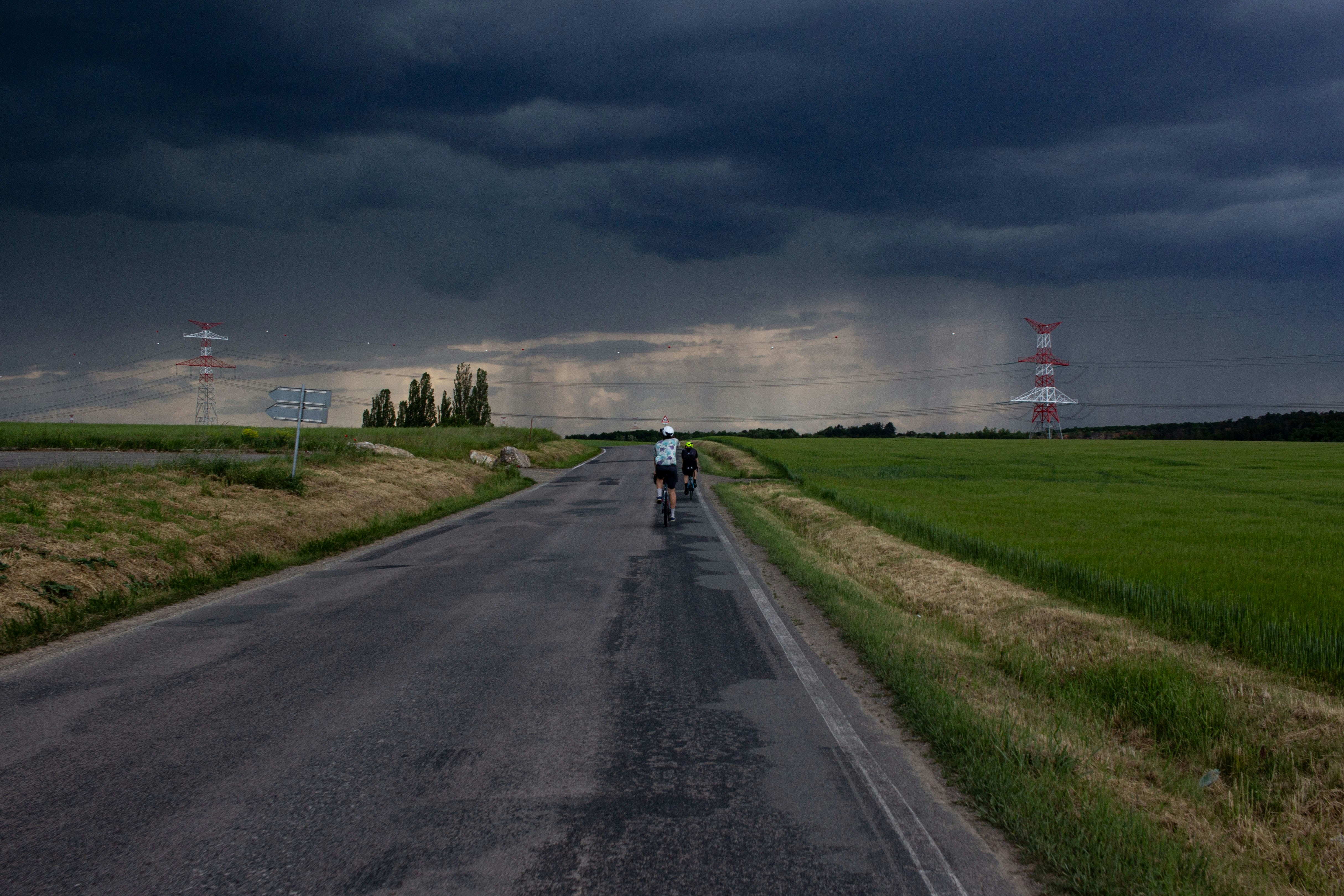 Cyclist on wet road under stormy sky with rain.