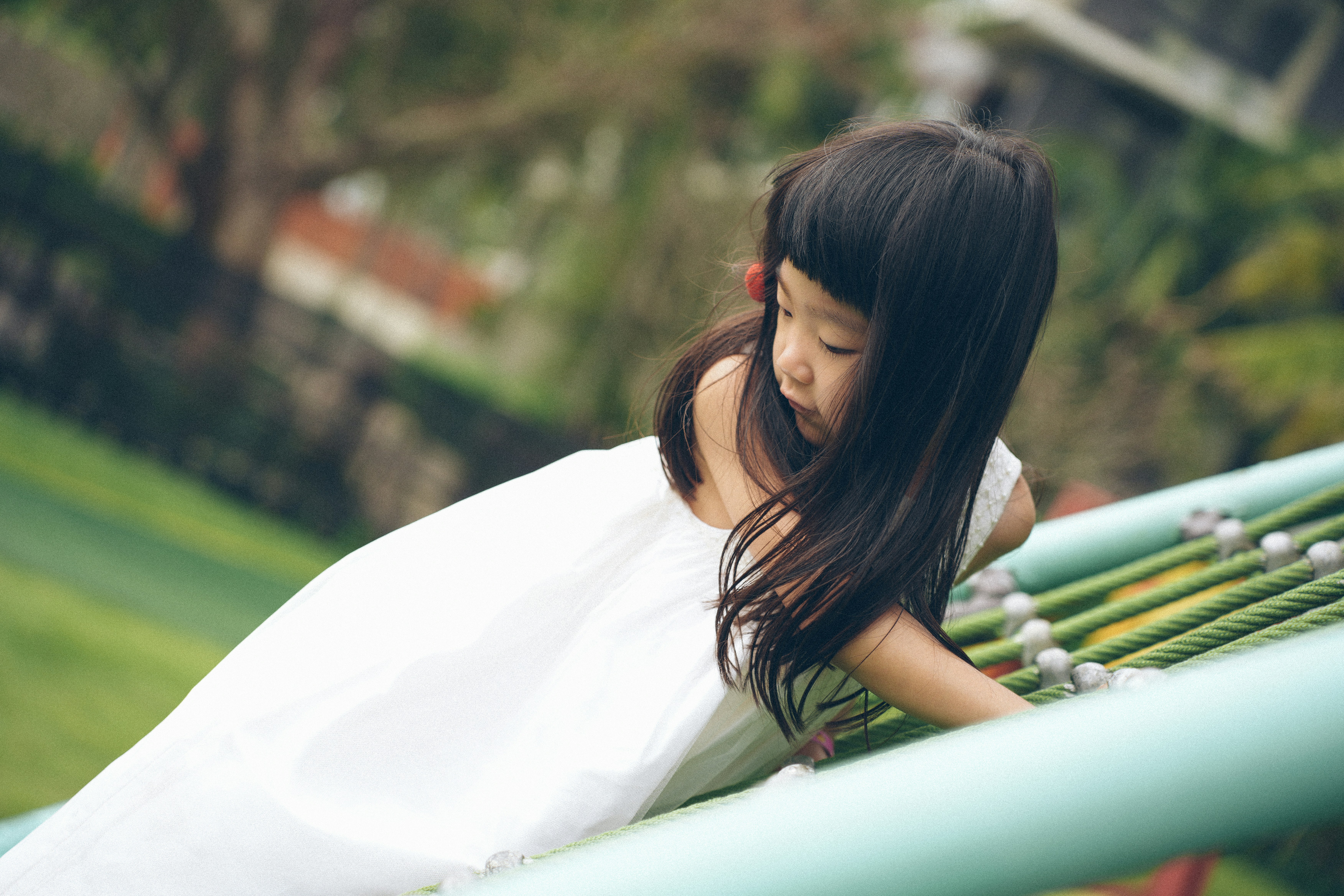 Young girl in white dress on playground equipment