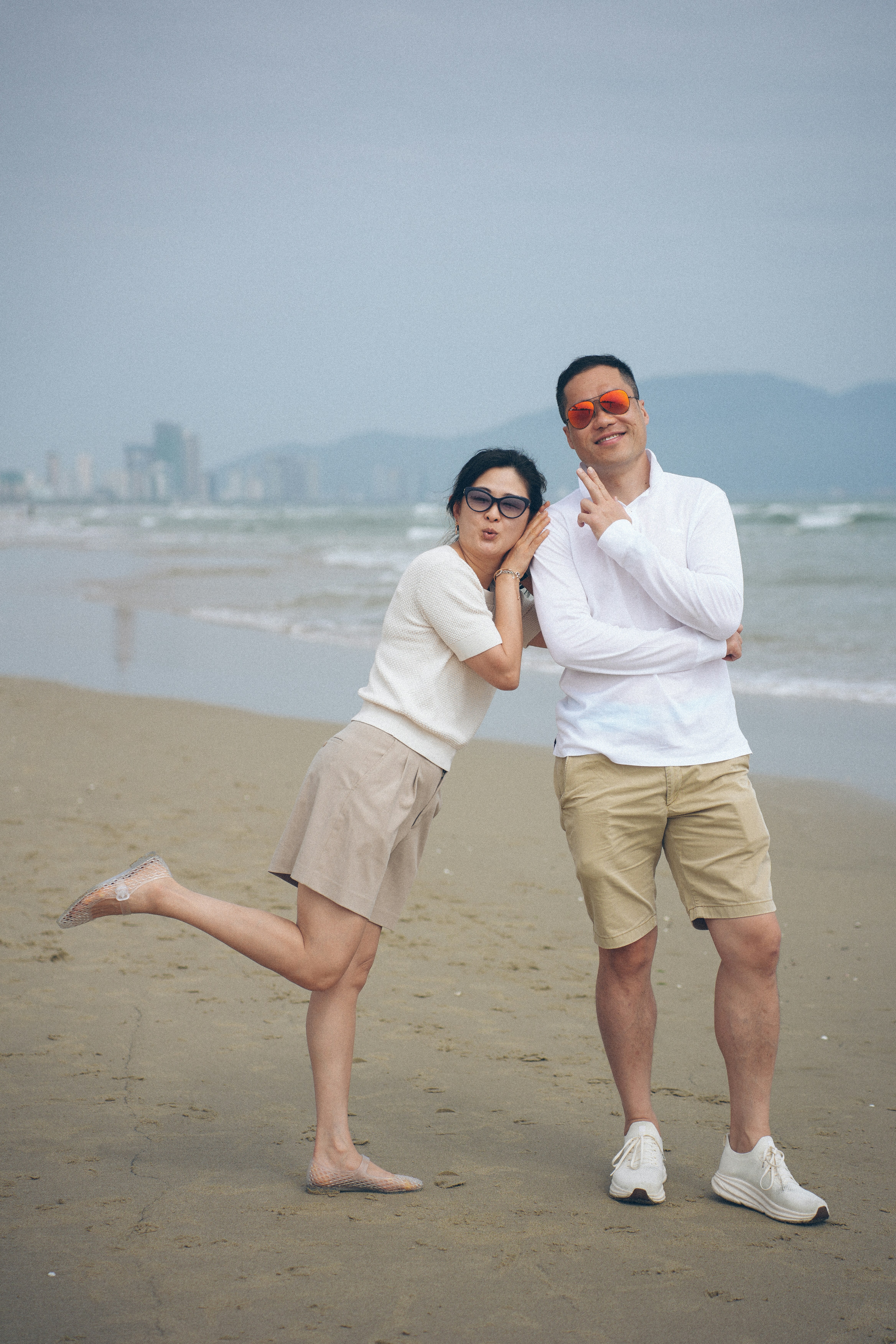 Couple posing playfully on a sandy beach.