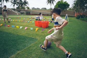 Young boy kicks a ball on a grassy field.