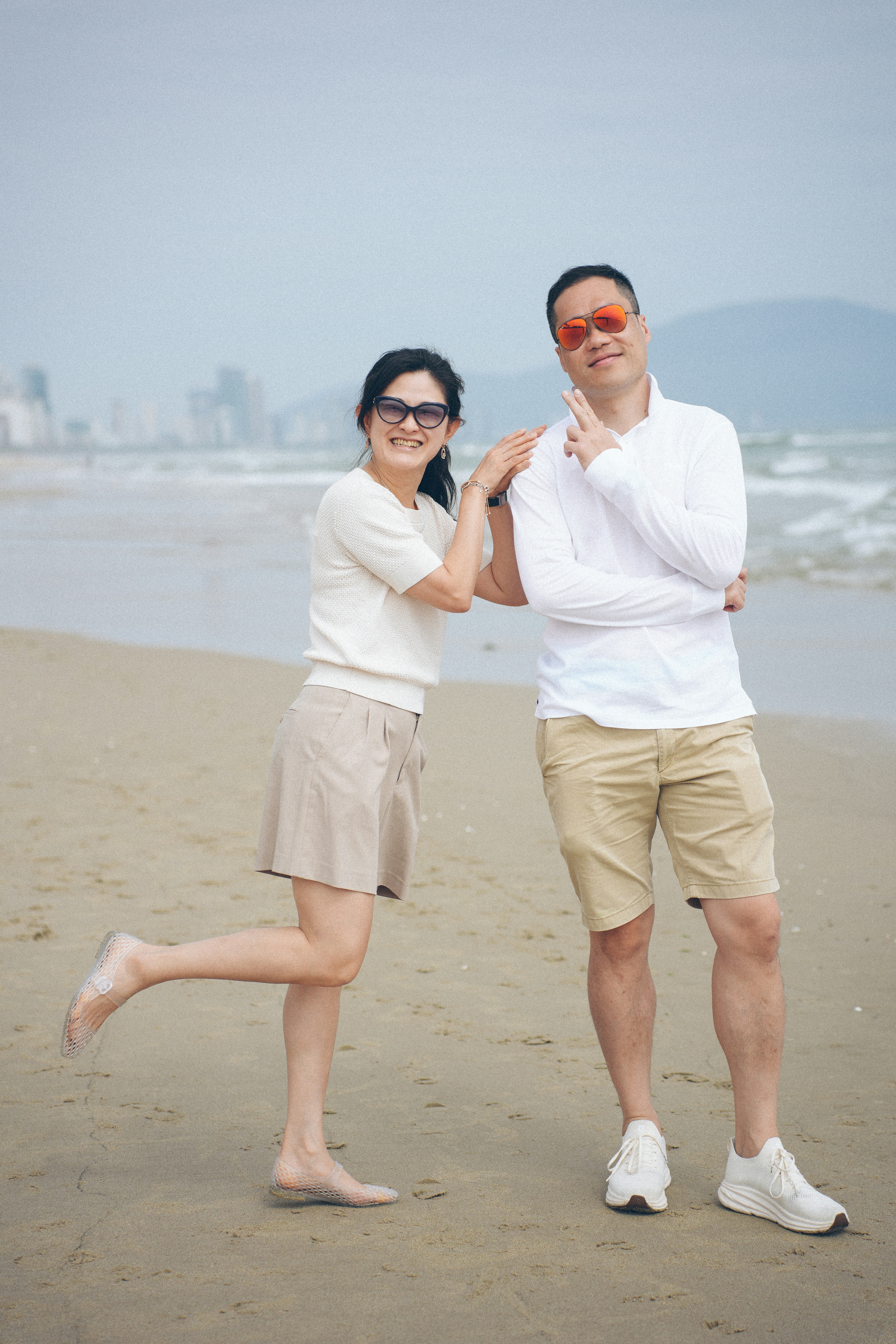 A couple posing on a sandy beach by the ocean