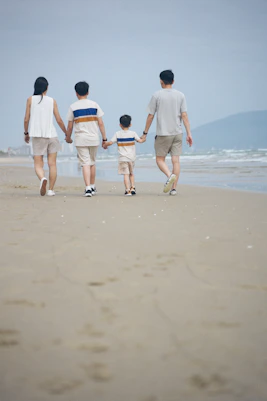 Family walking on a sandy beach near the ocean.
