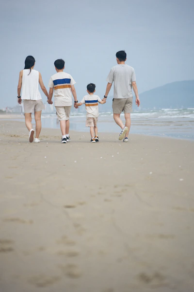 Family walking on a sandy beach near the ocean.
