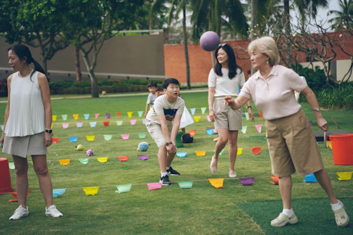 Adults and children playing a game with balls outdoors.