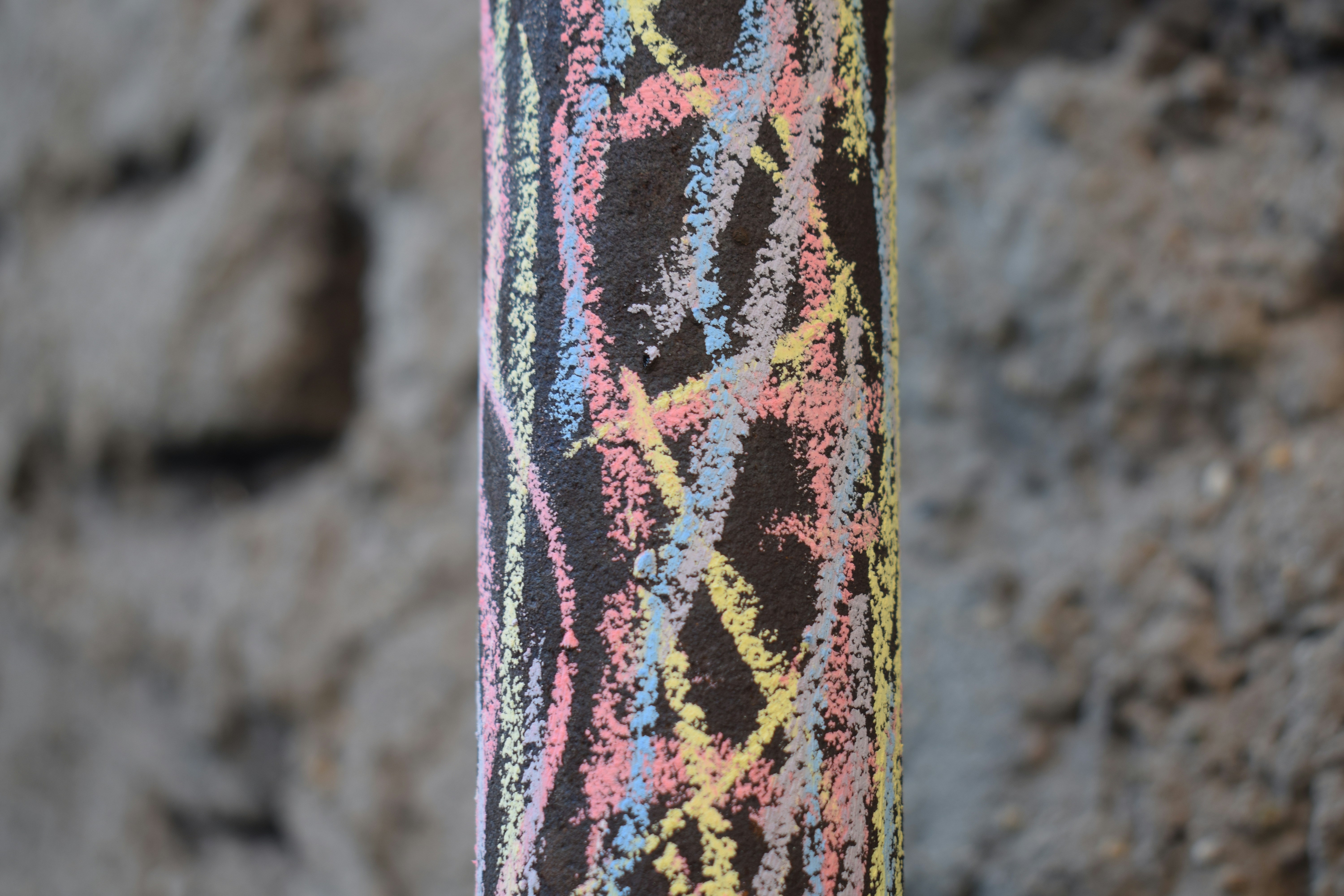 Colorful chalk scribbles on a dark cylindrical surface