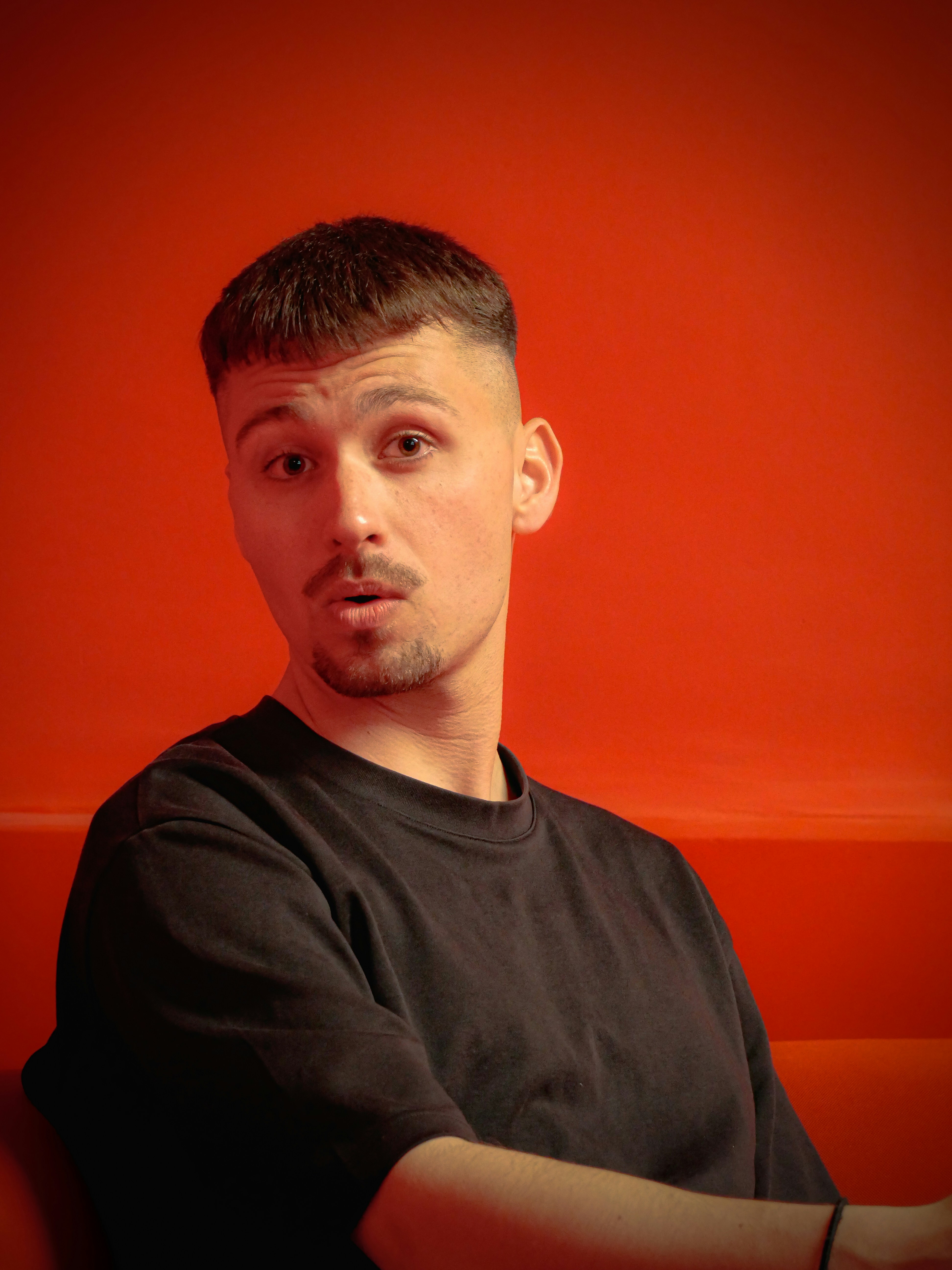 Man with short hair wearing a black t-shirt.