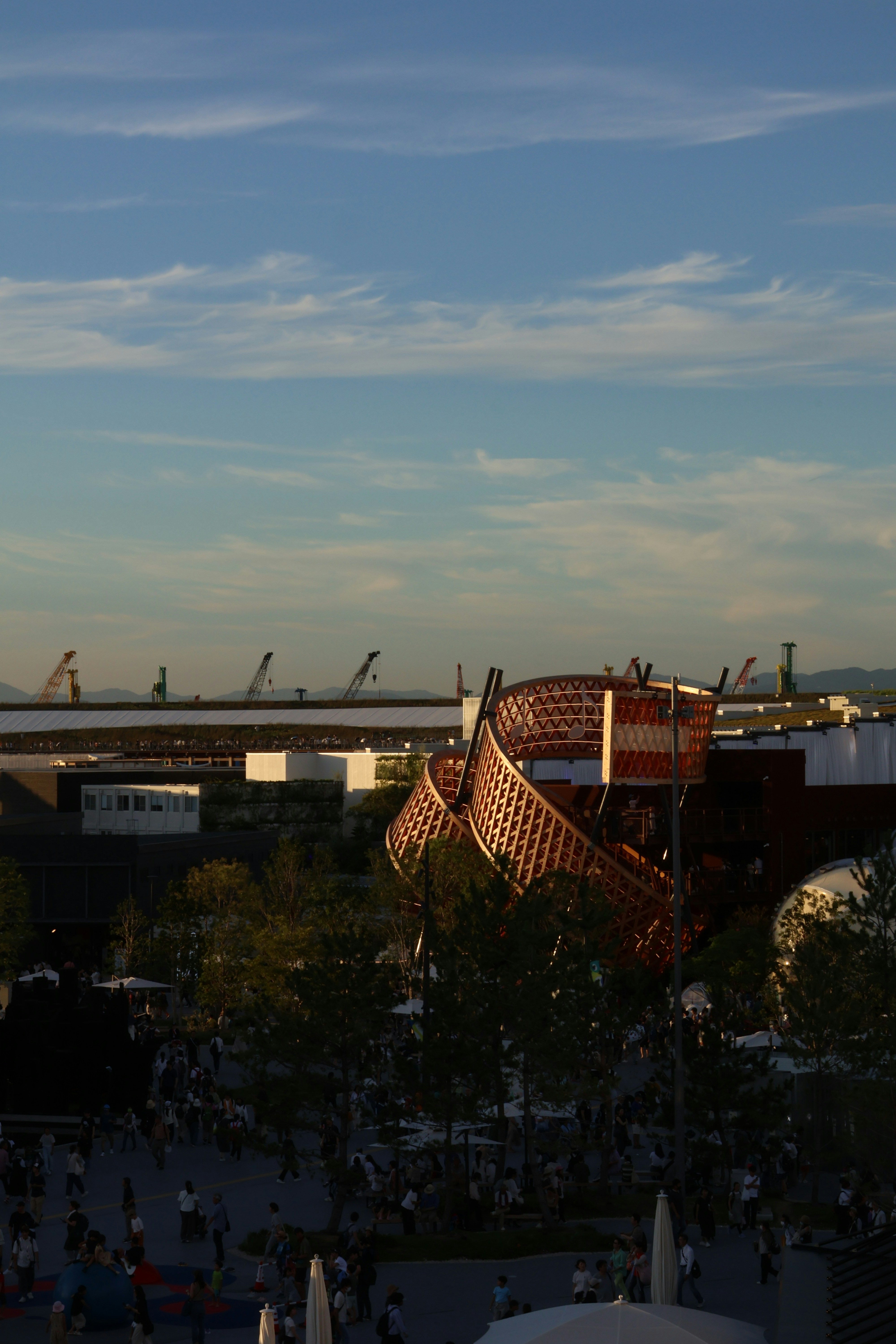 Modern sculpture in a bustling urban park at sunset