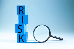 Blue blocks spelling risk next to a magnifying glass