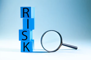 Blue blocks spelling risk next to a magnifying glass.