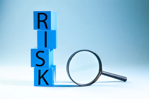 Blue blocks spelling risk next to a magnifying glass.