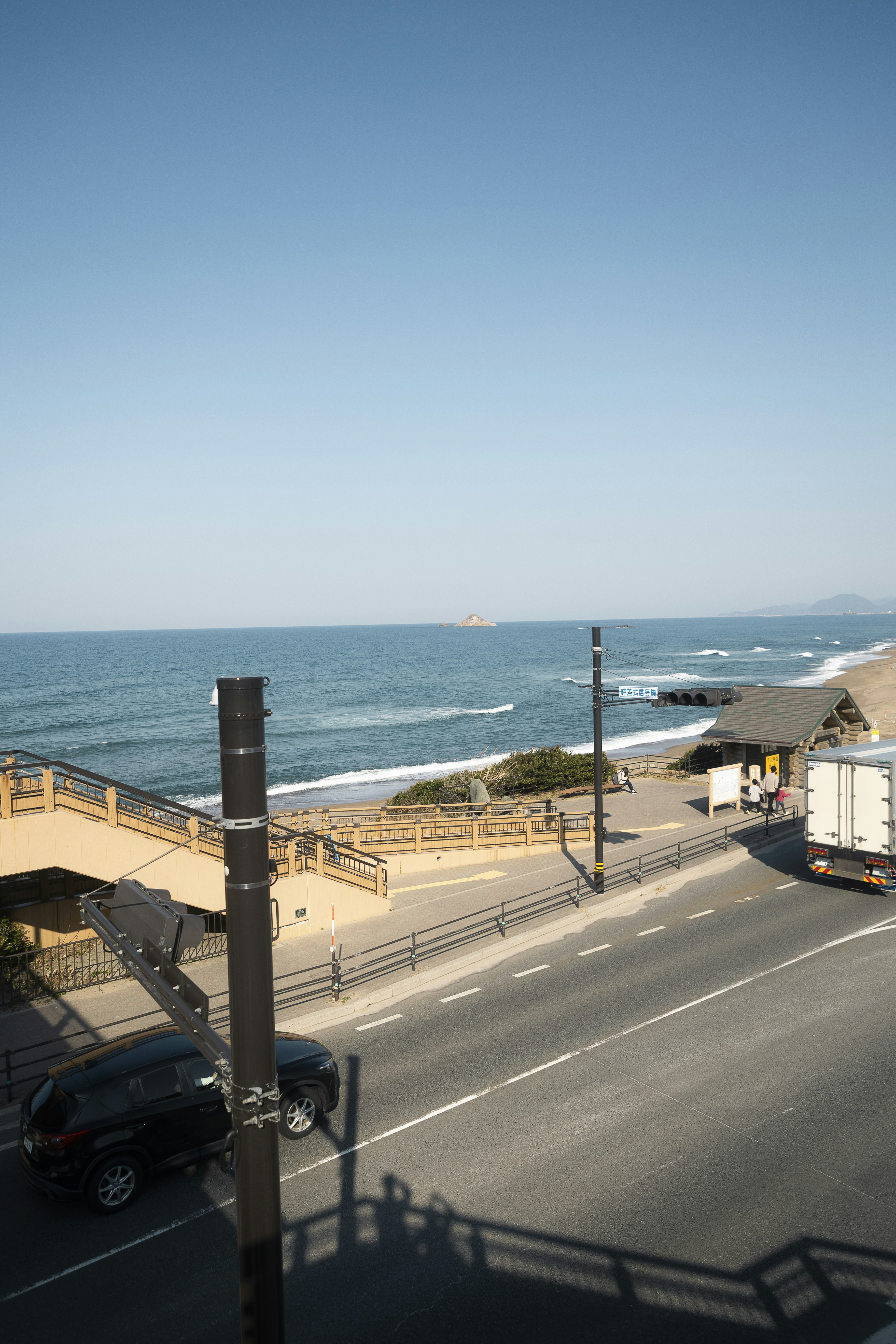 Coastal road with ocean waves and clear blue sky.