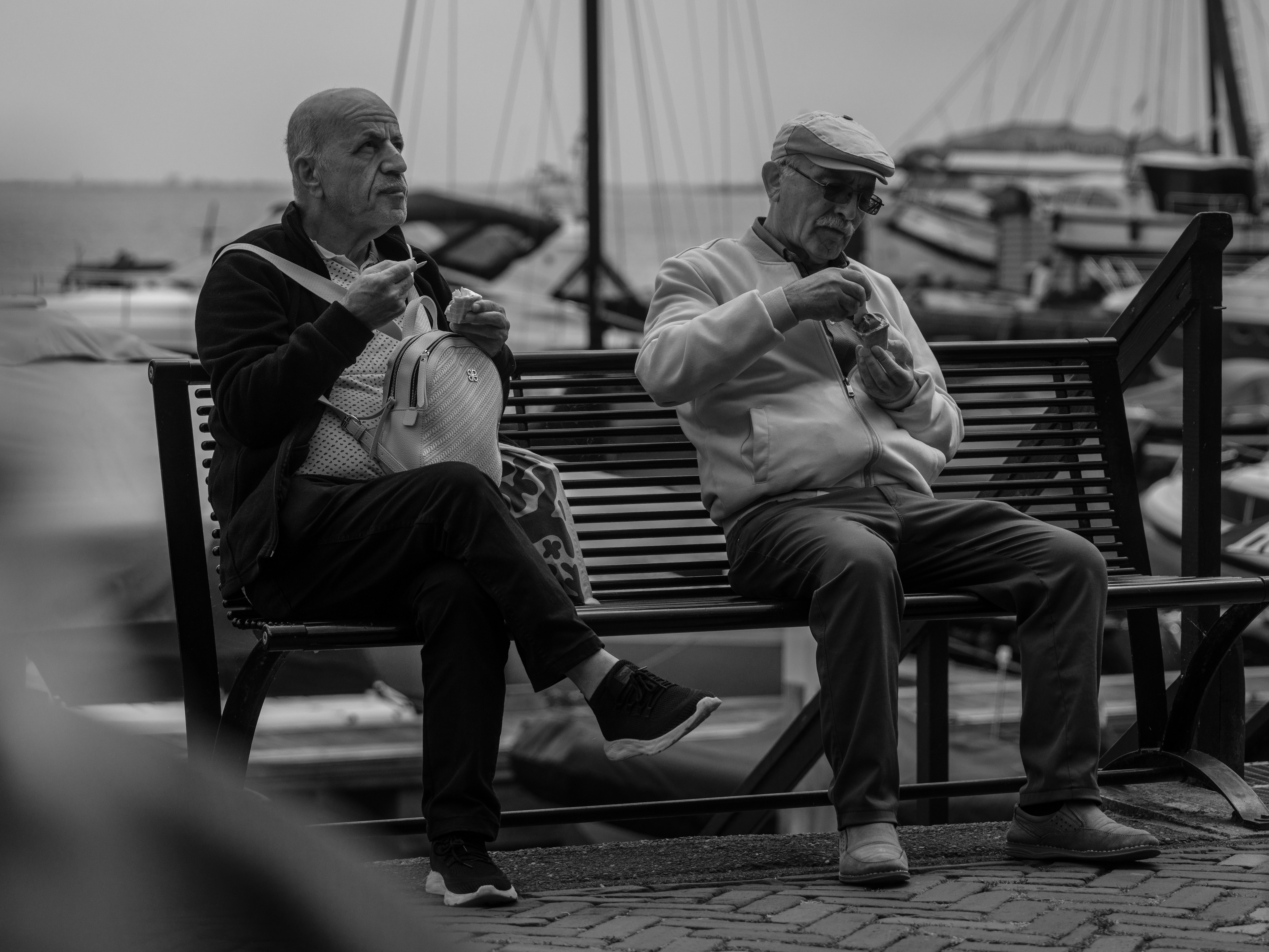 Two men sitting on a bench eating food
