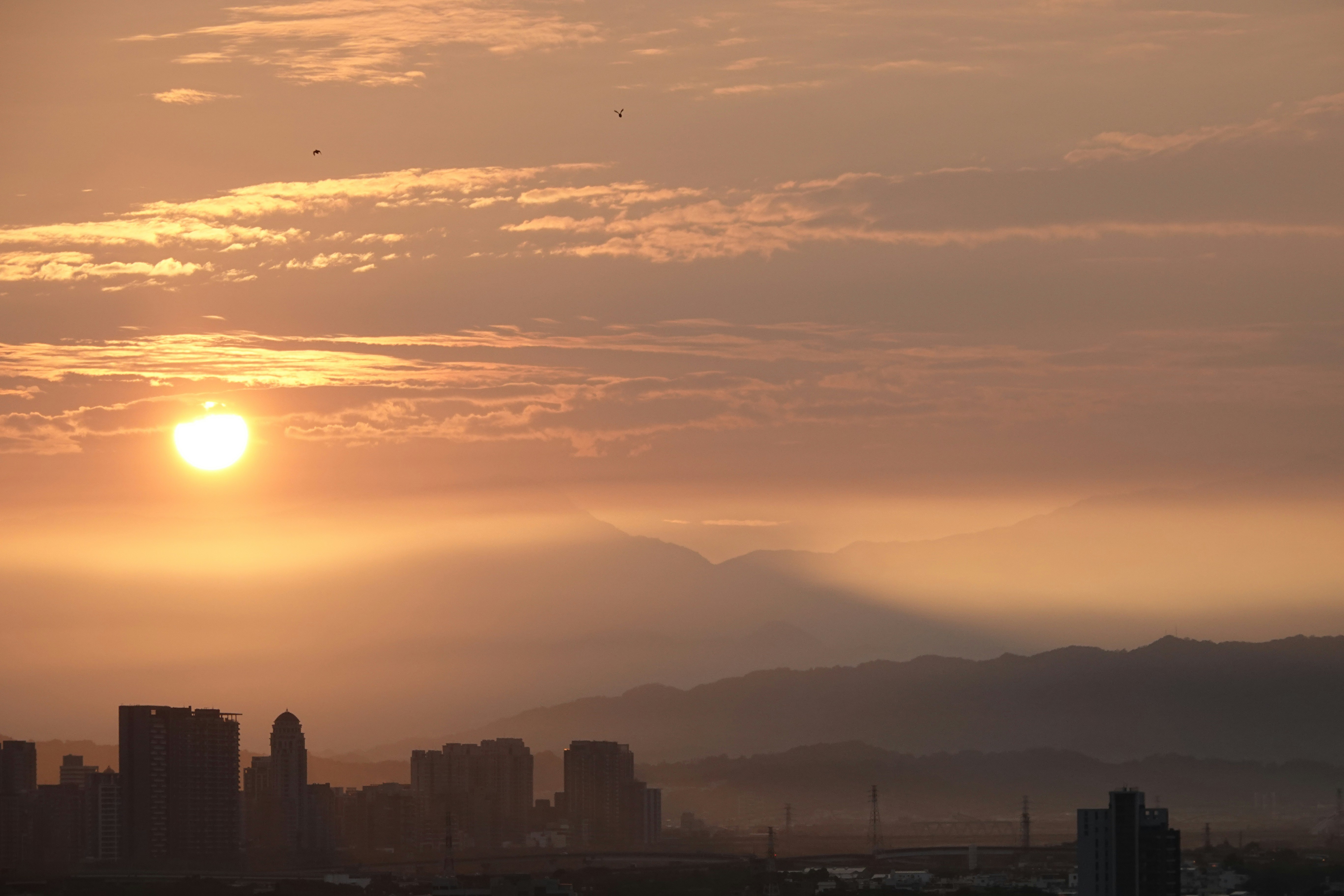 Sunrise over a misty cityscape with mountains in background