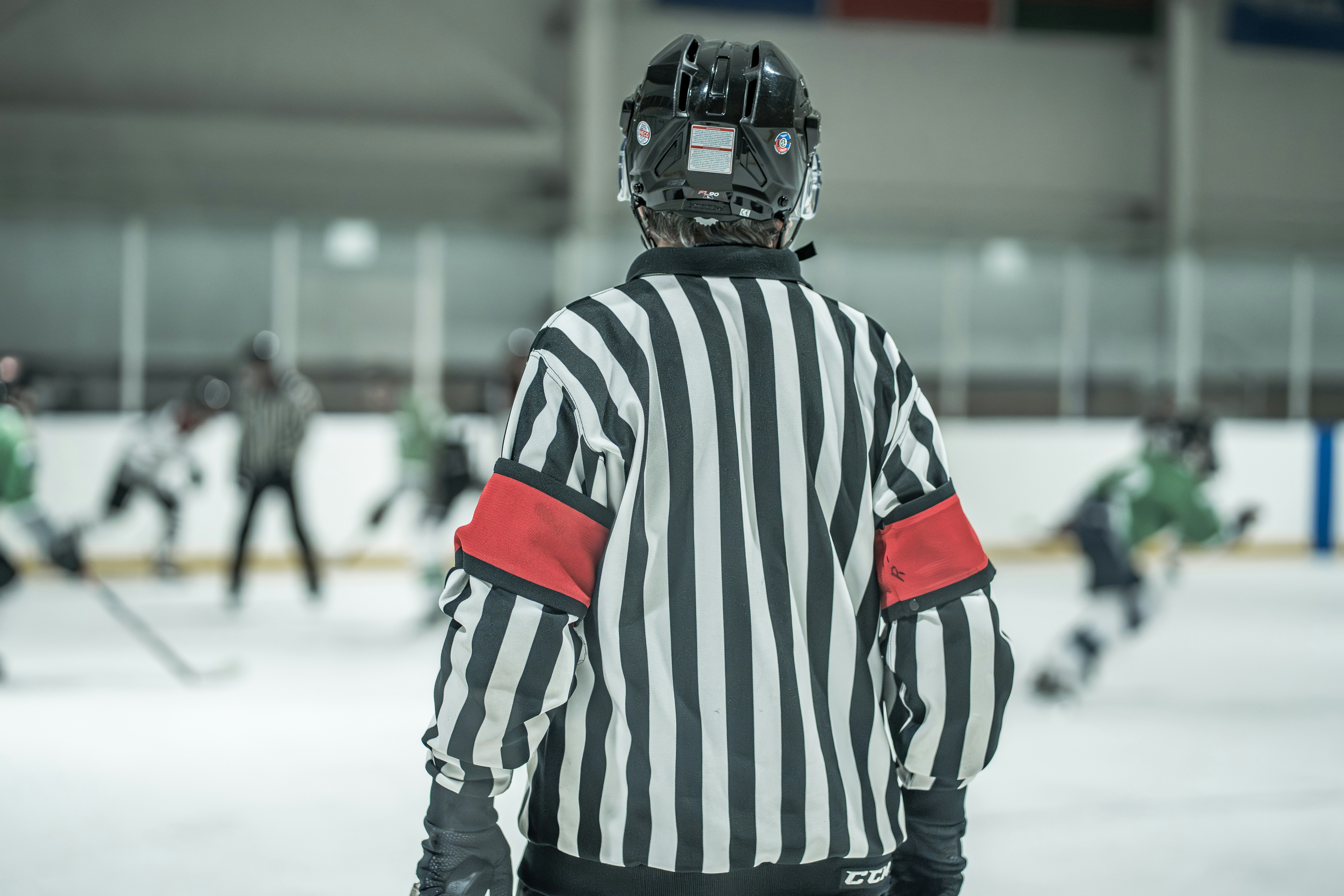 Hockey referee in black and white stripes on ice.