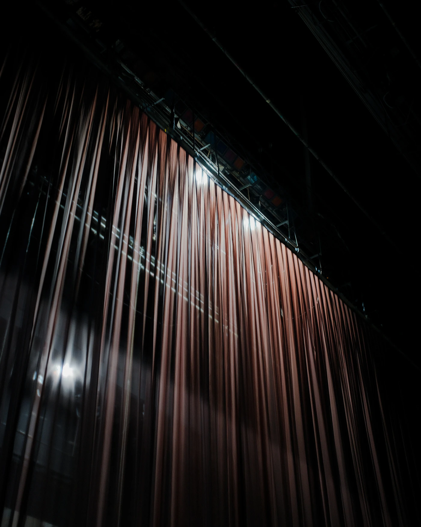 A closed stage curtain in a dark theatre