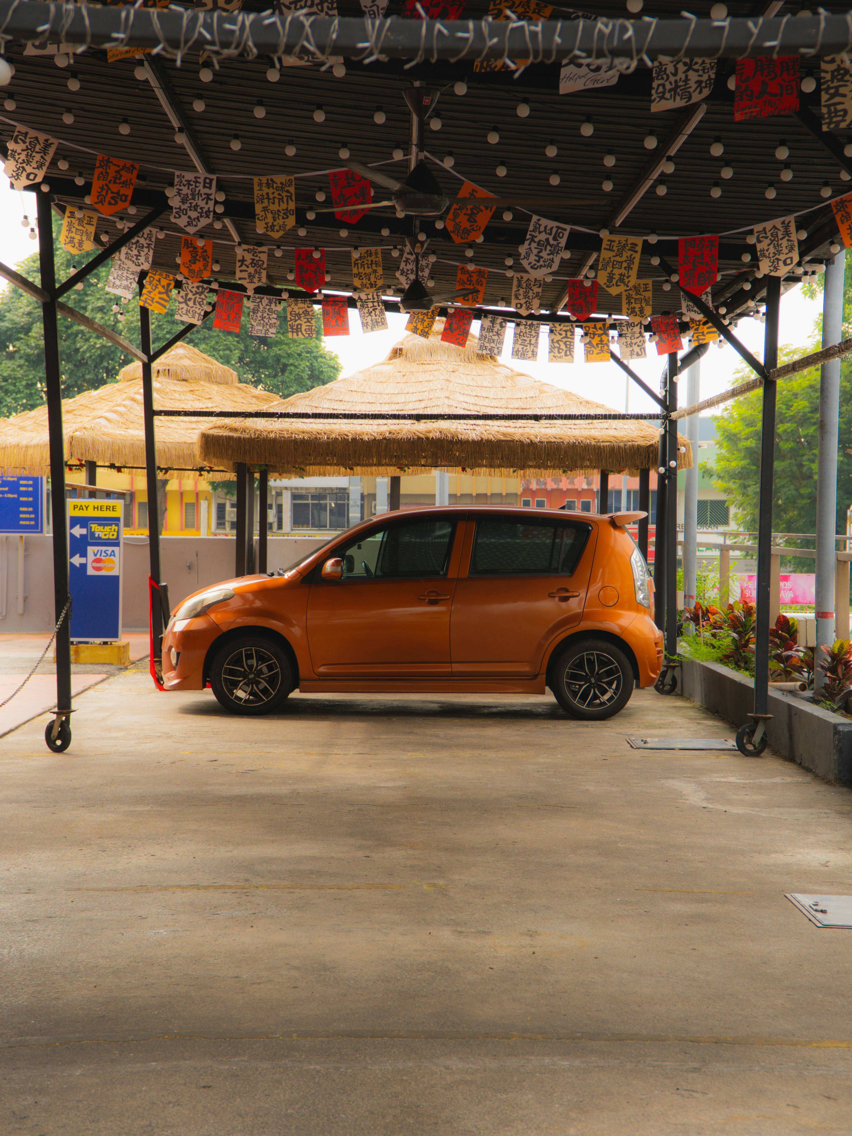 An orange hatchback car parked under a decorated canopy.