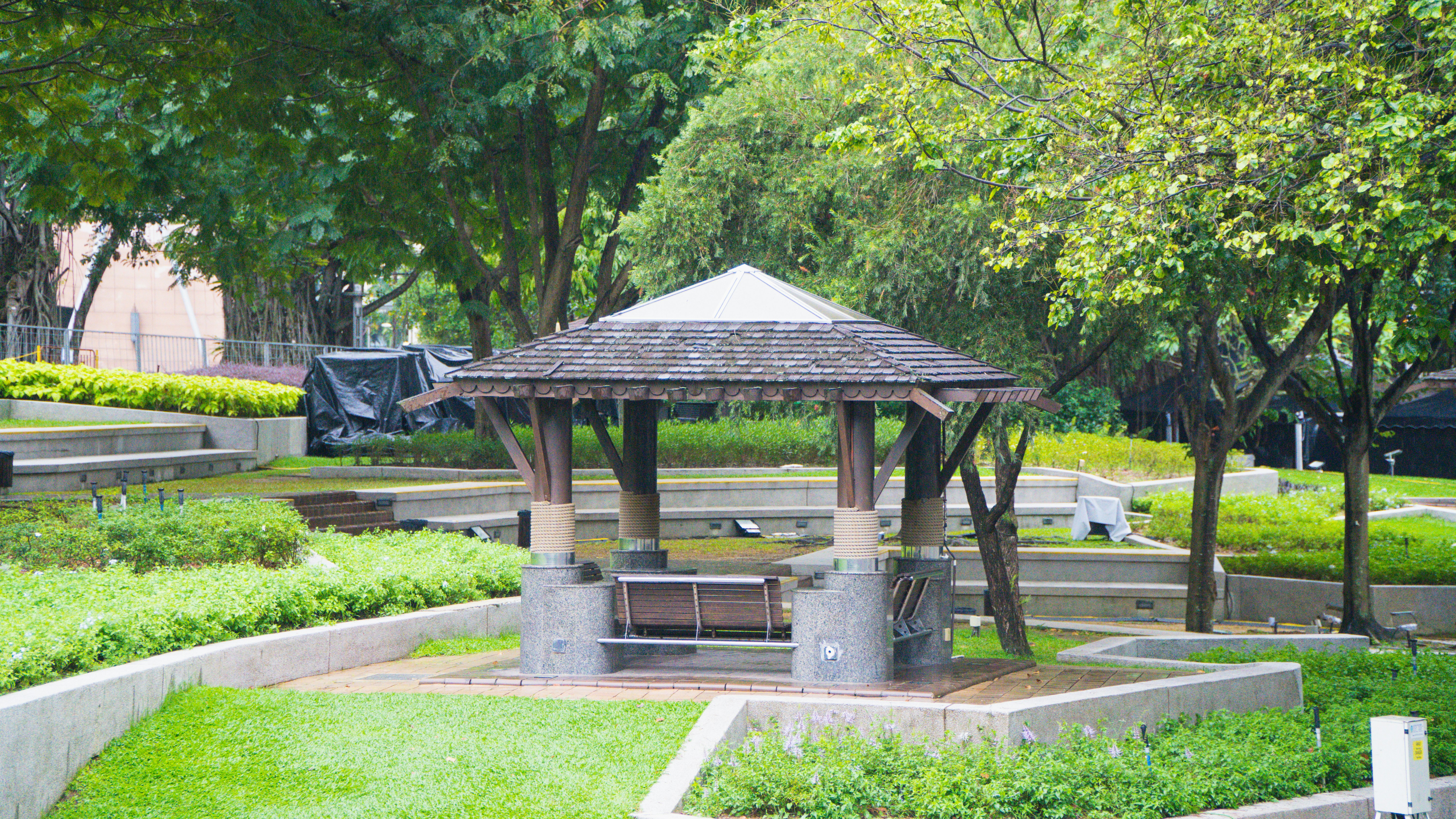 Un cenador de madera en un parque verde y frondoso.