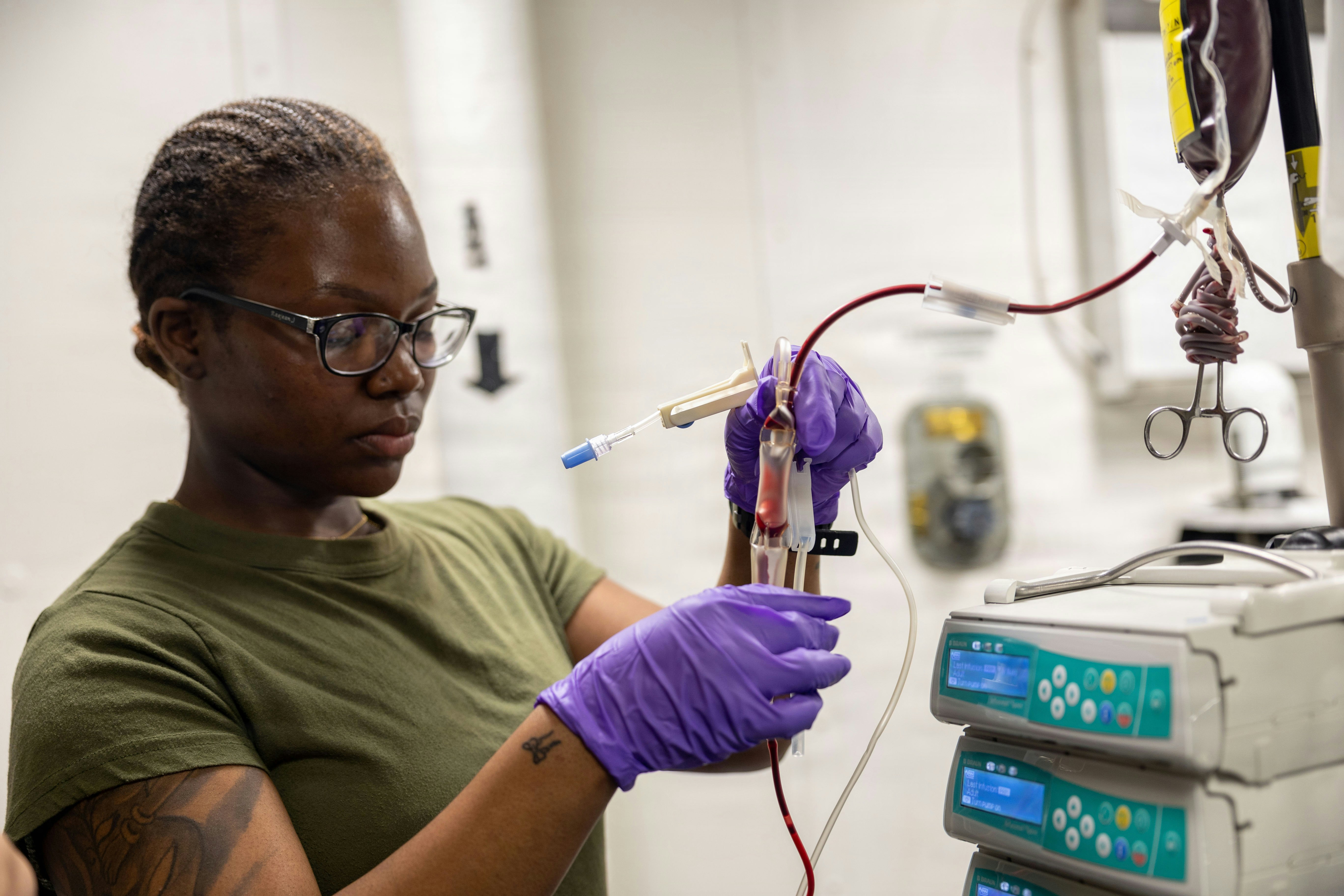 A woman in purple gloves works with medical equipment.