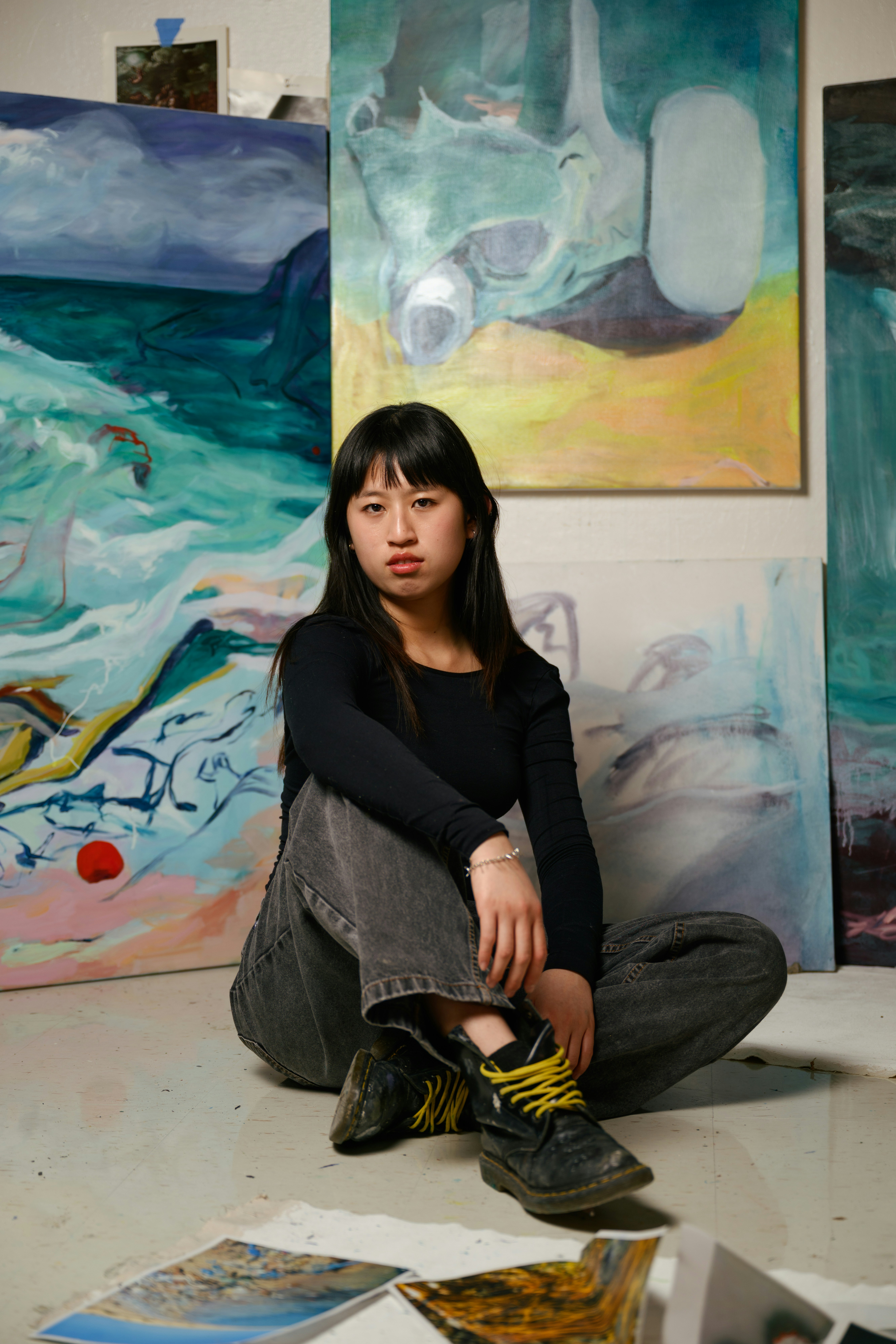 Young artist sitting among her abstract paintings