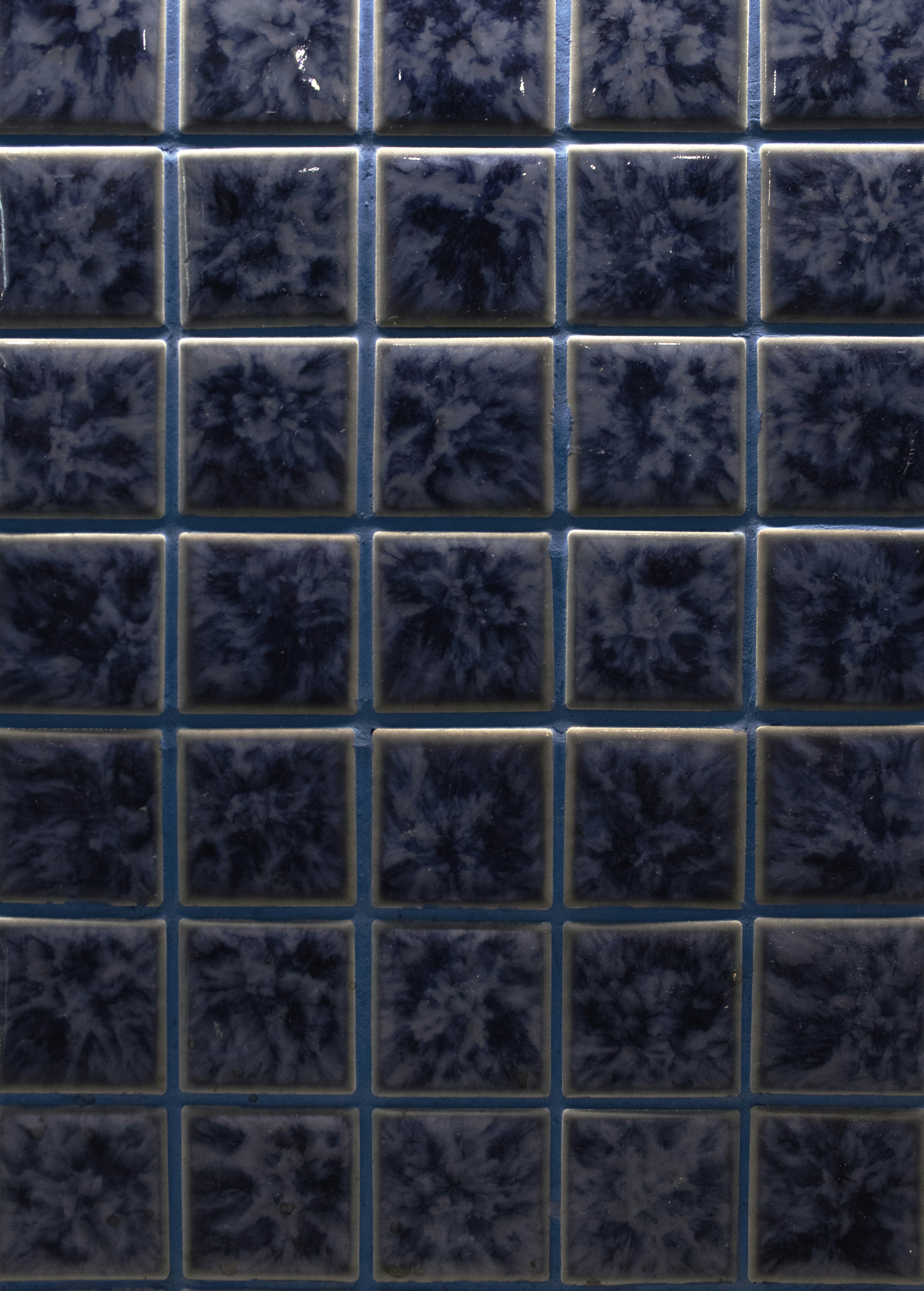 Un gros plan de carreaux carrés marbrés bleu foncé.