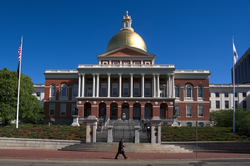 Massachusetts State House with golden dome and flags against a blue sky