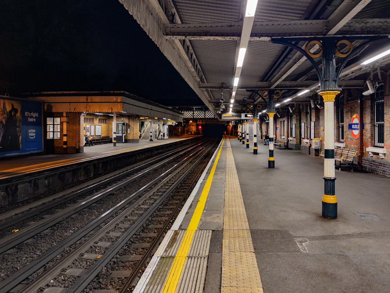 An empty railway platform at night under bright overhead lights