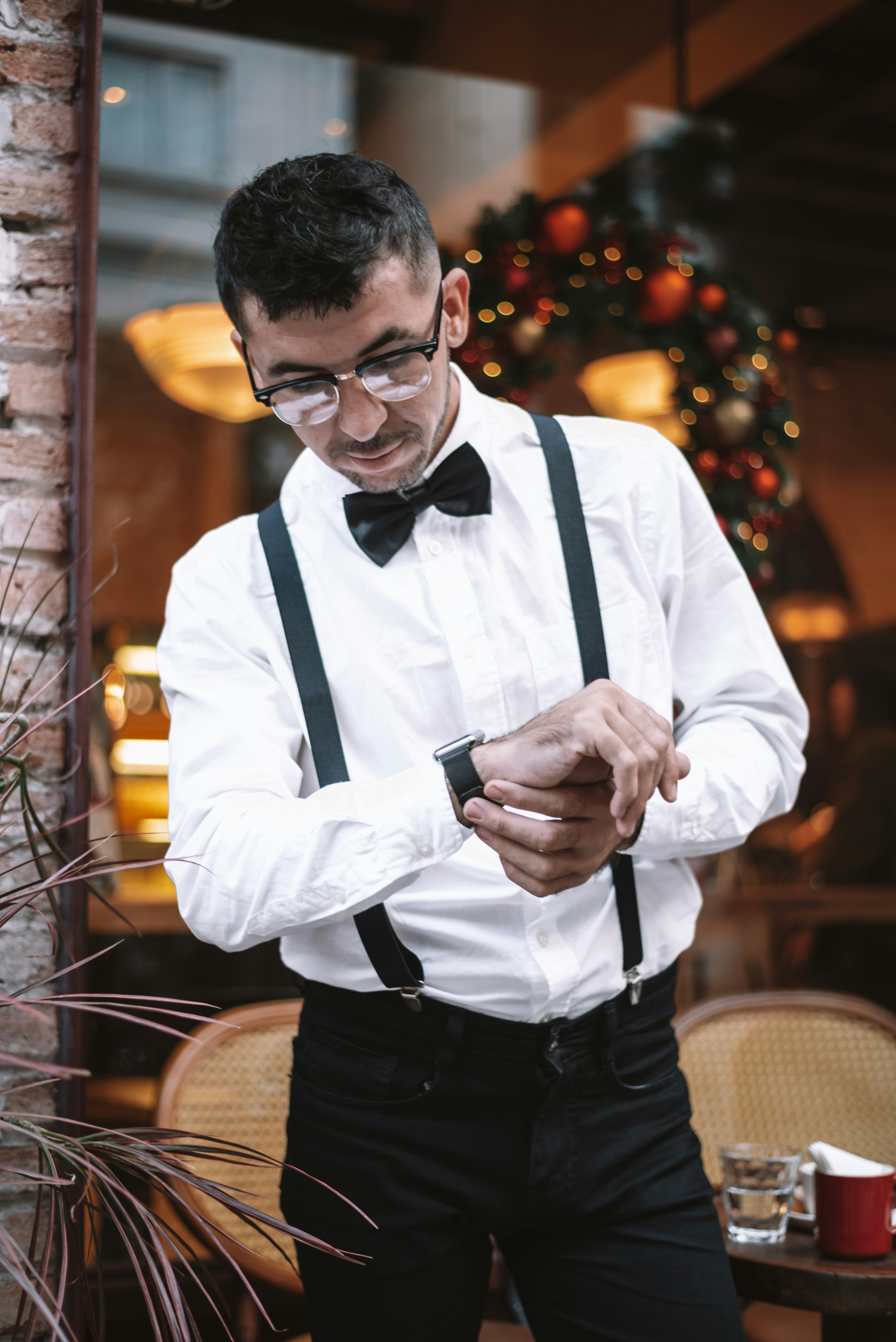 Man in bowtie and suspenders checks his watch