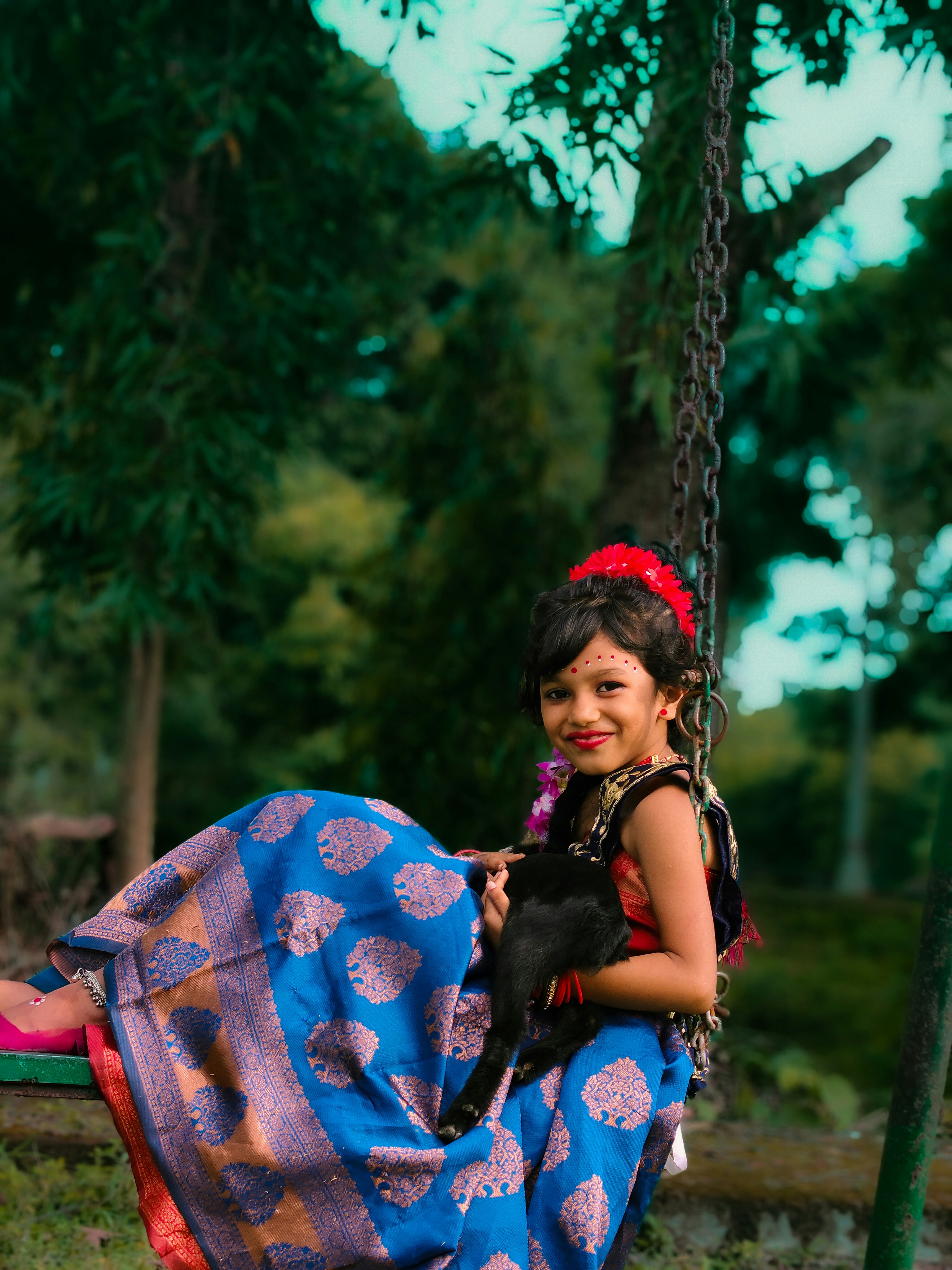 Young girl in traditional dress on a swing with cat