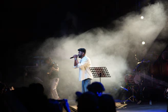 A man sings on stage with smoke and lights.