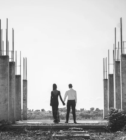 Couple holding hands amidst unfinished concrete structures