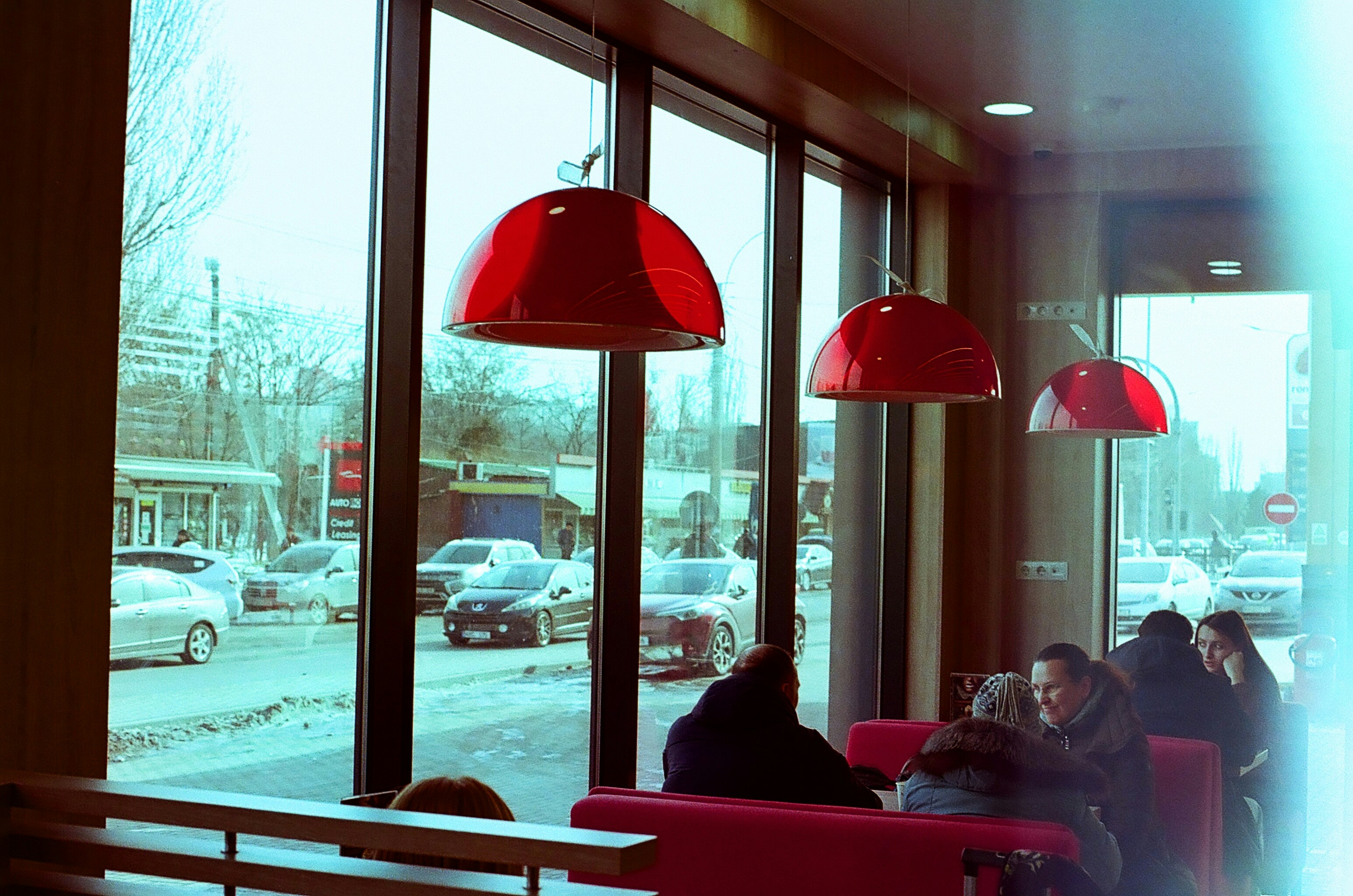 People sit at booths inside a cafe with large windows.