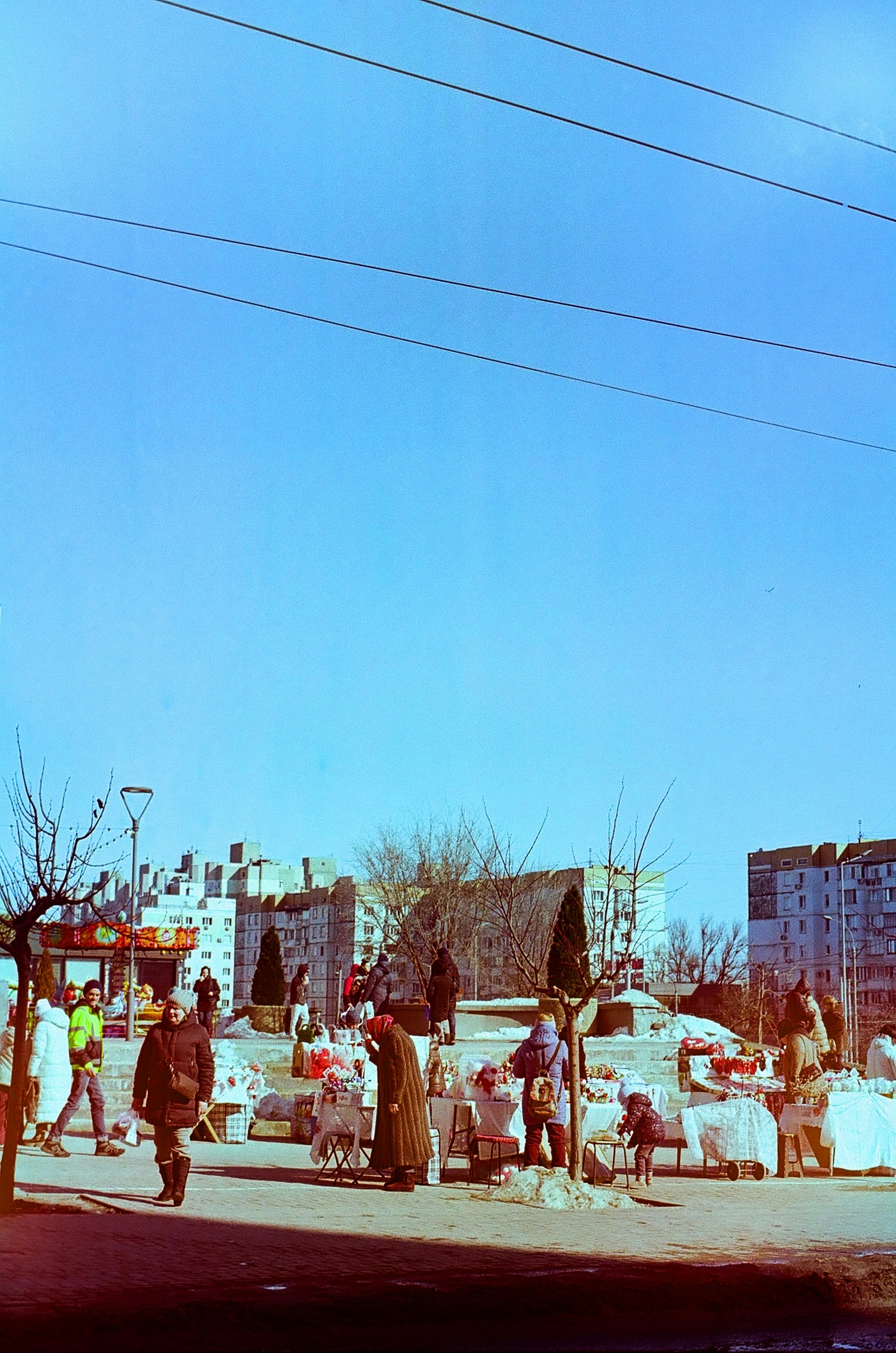 People gathered at an outdoor market on a sunny day.