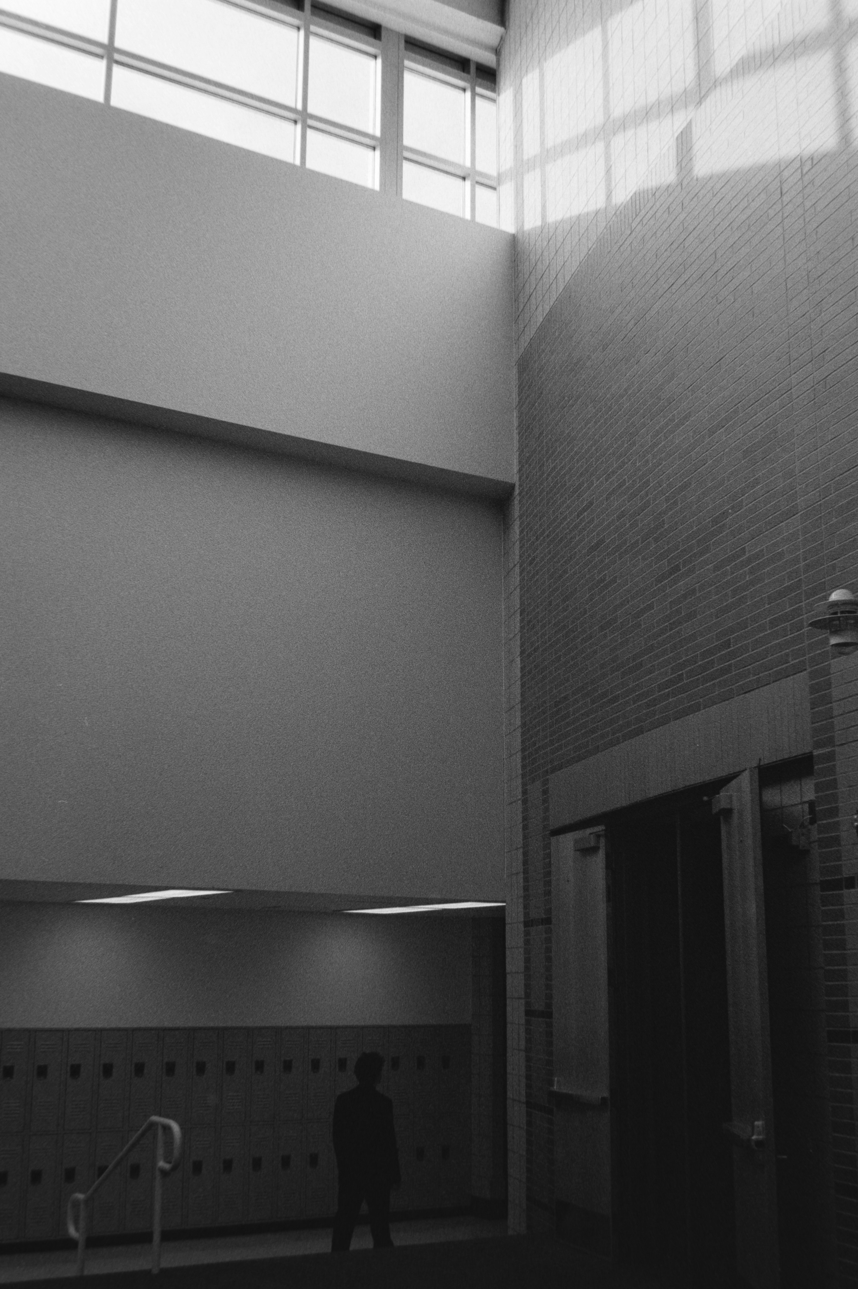 一人の人物が現代的な陽光の差し込むアトリウムに立っている。