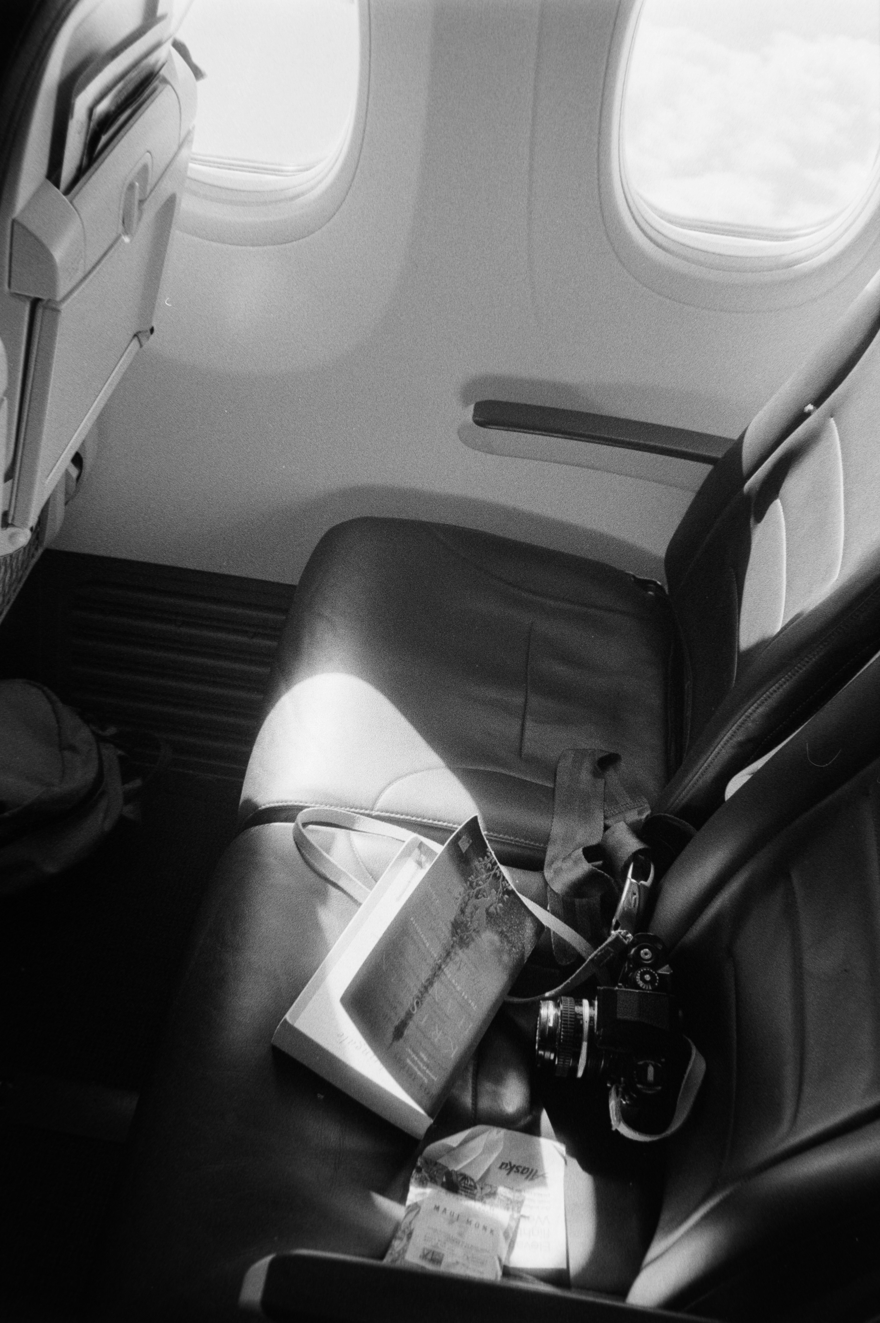 Empty airplane seats with a book and camera.