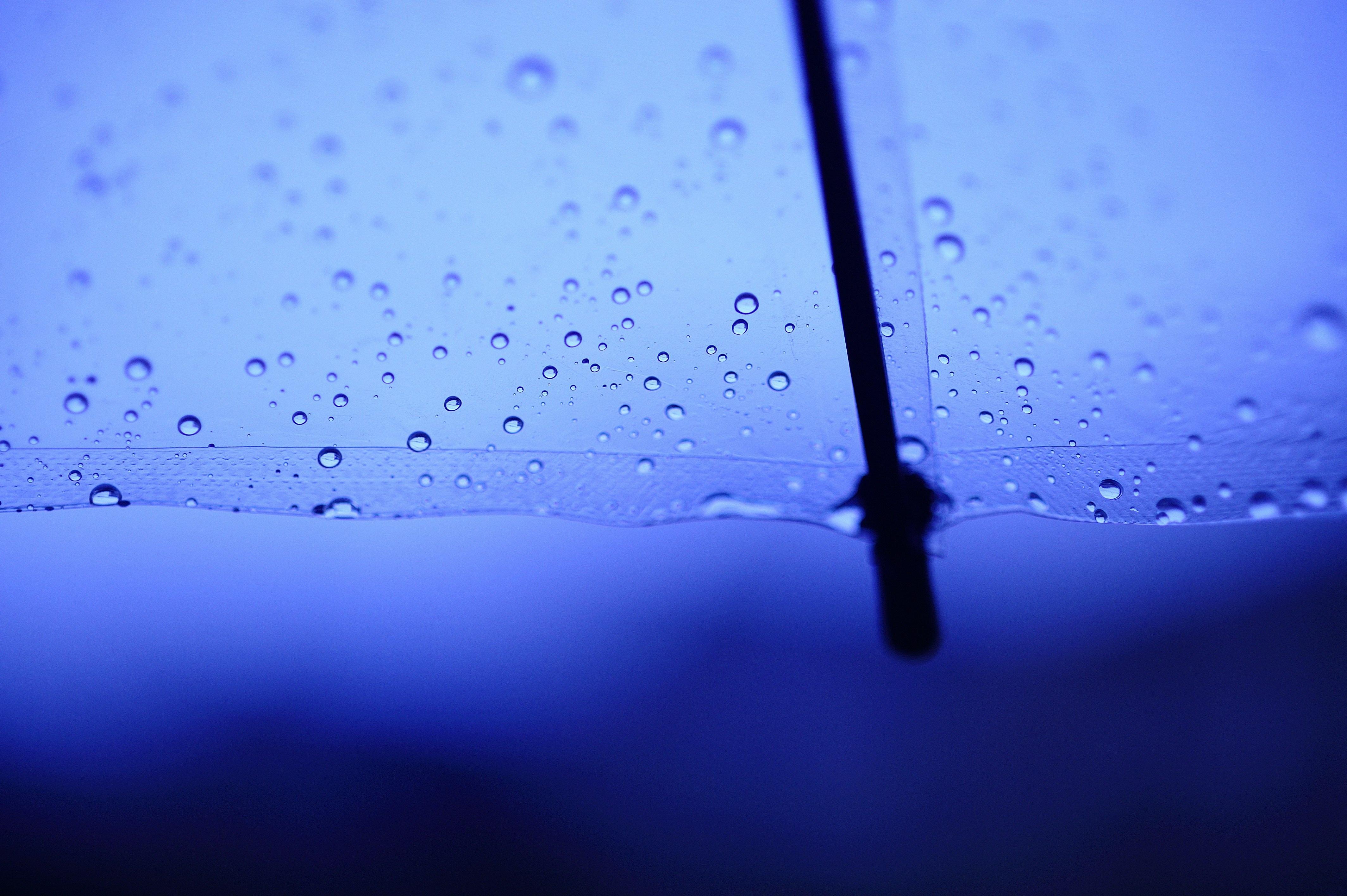 Gotas de agua sobre un paraguas azul con fondo oscuro