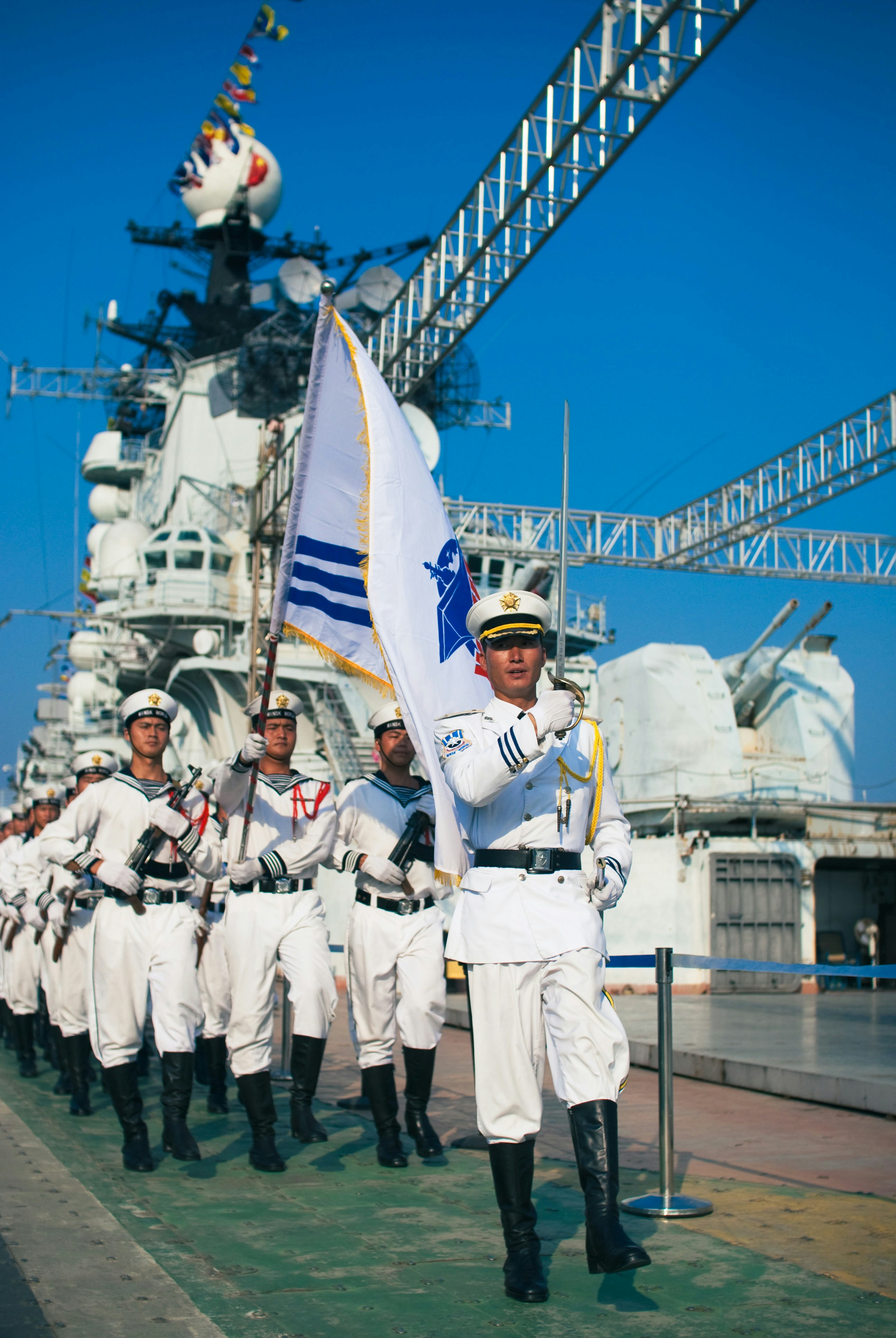 Des marins en uniforme marchant avec un drapeau sur un navire.