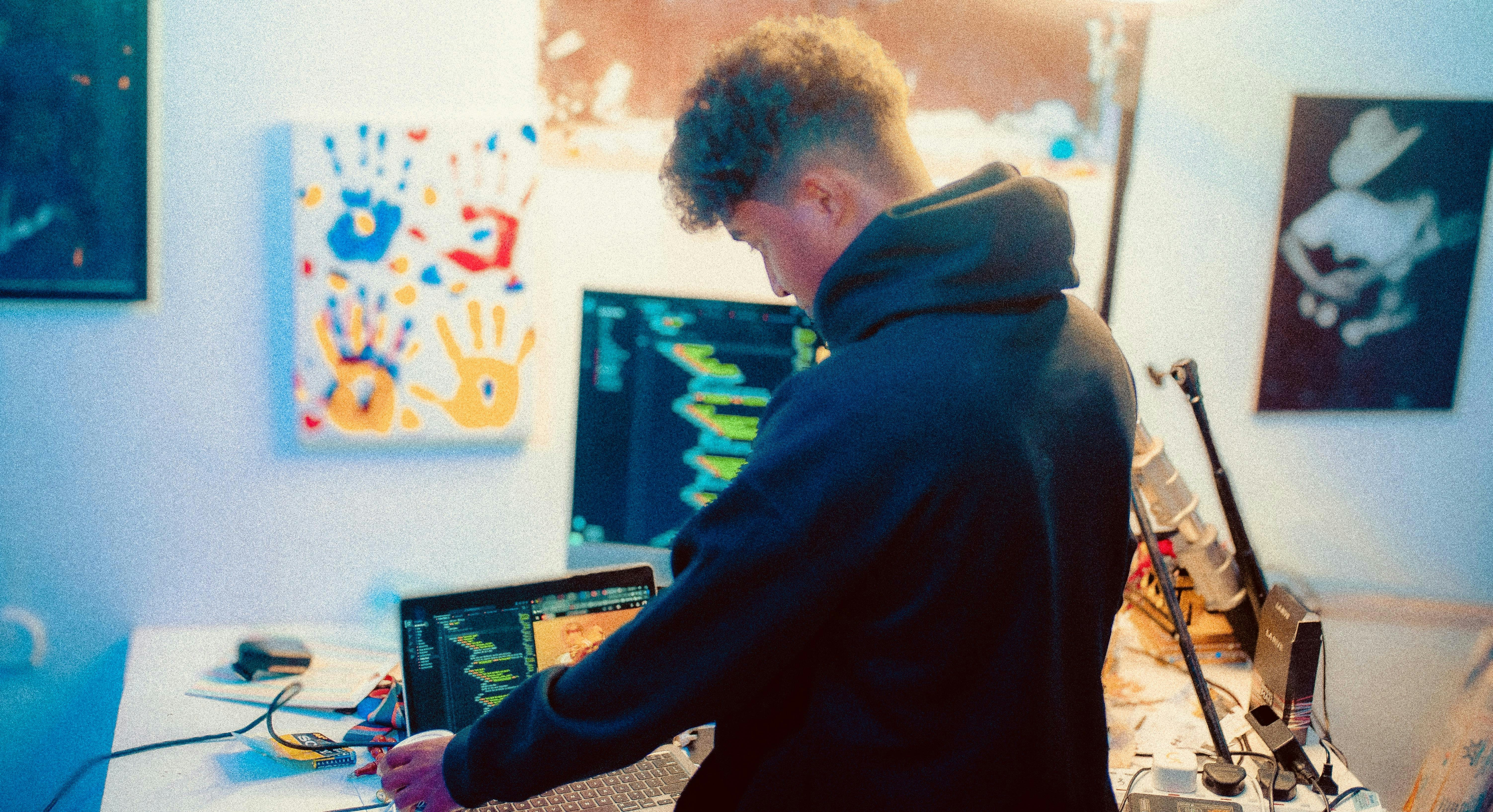 Young man working on laptop and computer screens