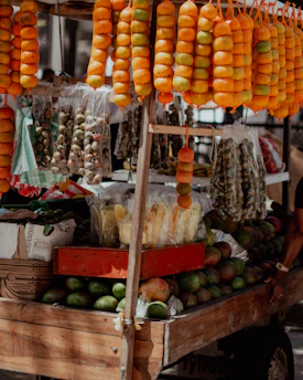 A fruit stand displays oranges, mangoes, and other produce.