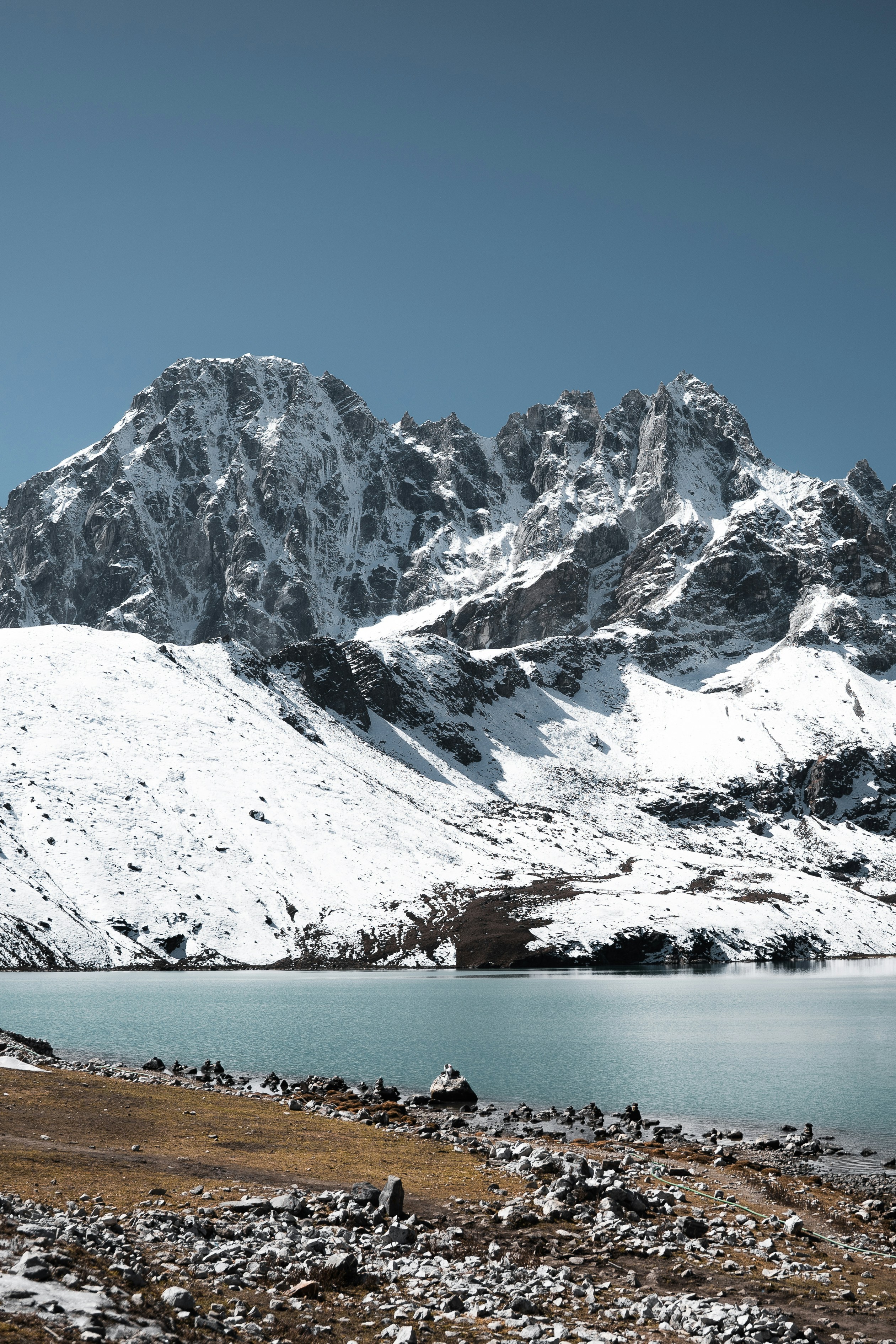 Schneebedeckte Berge überblicken einen ruhigen See unter klarem Himmel