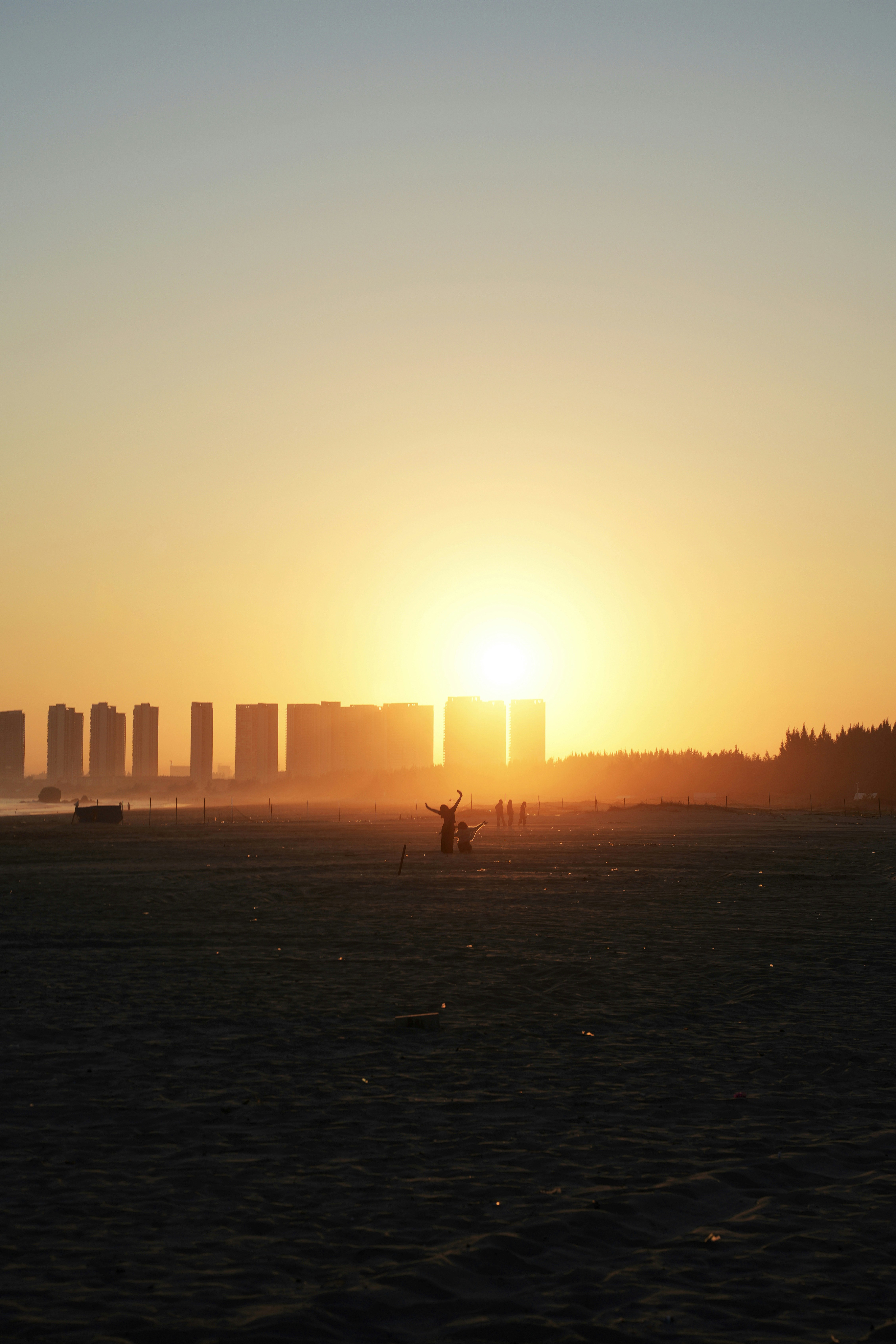 Silhouettes of buildings against a bright sunset sky.