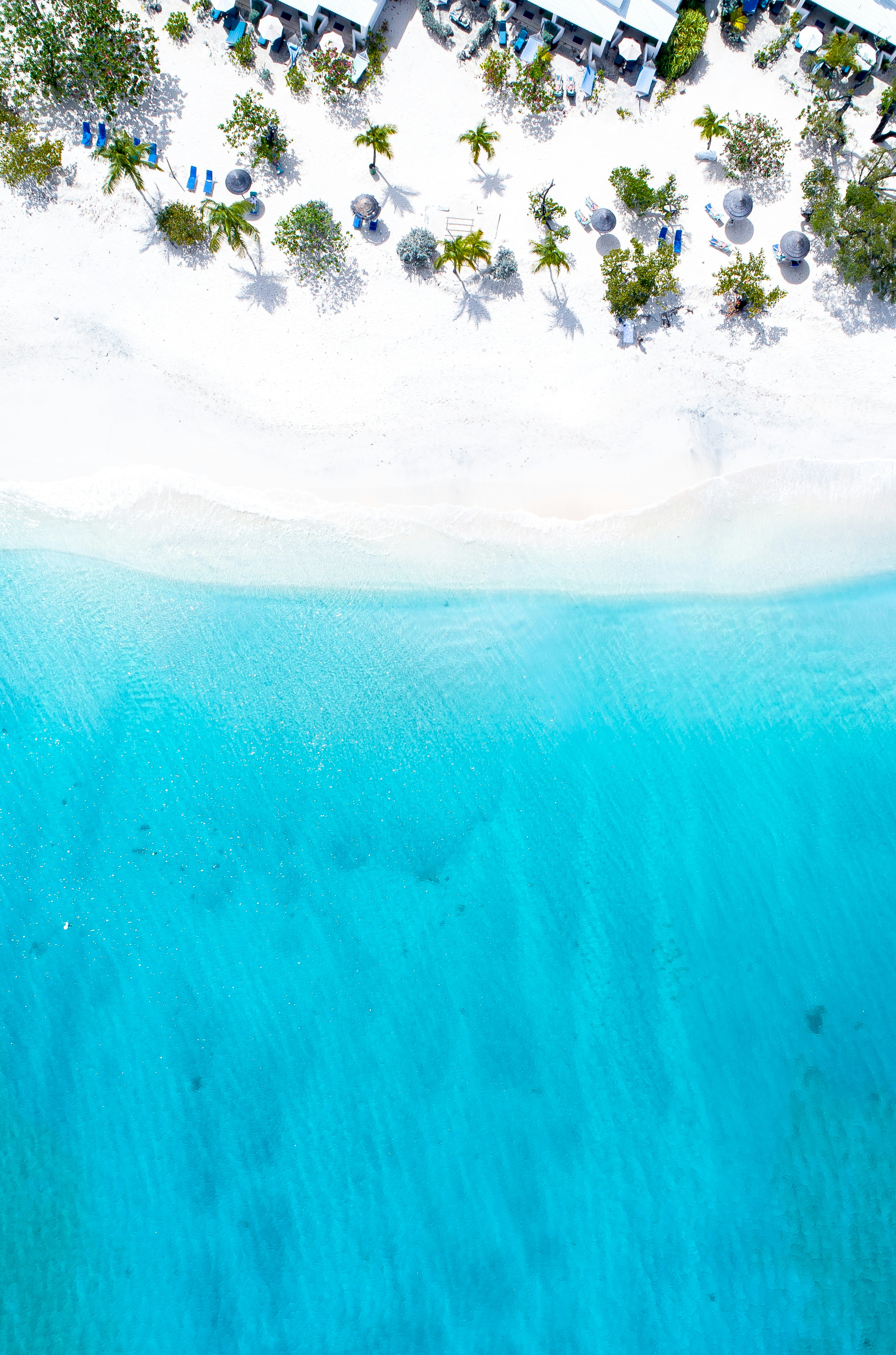 Vue aérienne d’une plage tropicale à l’eau turquoise.
