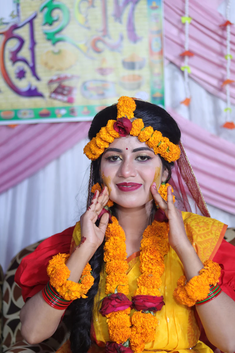 Smiling bride covered in marigold flowers and turmeric during a haldi ceremony