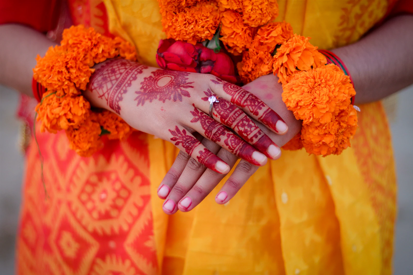 Mehndi-covered hands holding marigolds during a pre-wedding ritual.